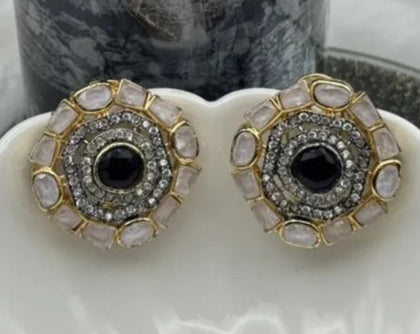 Pair of gold-plated and American diamonds earrings with black center stones and gold and silver accents on a white surface.