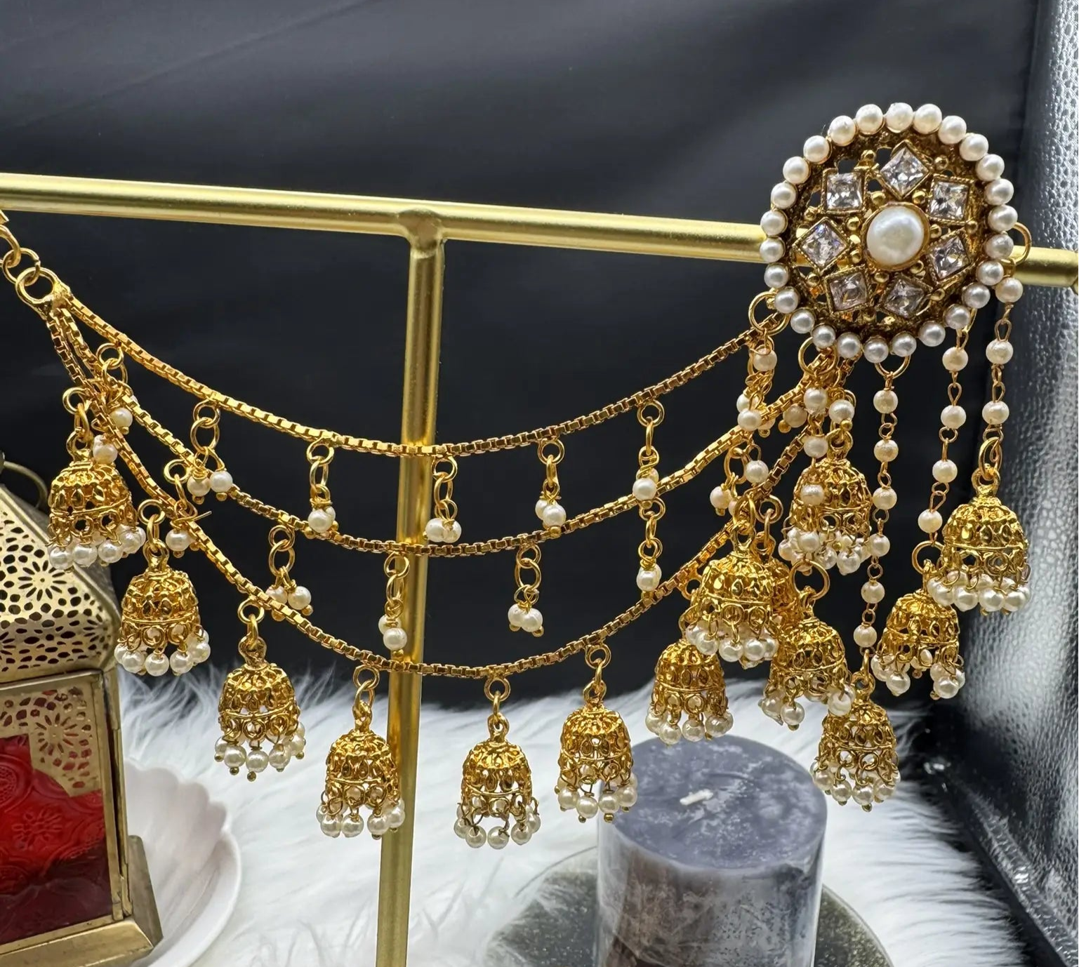 A pair of stainless steel and gold plated earrings with intricate saharas and hanging details, displayed against a dark background.
