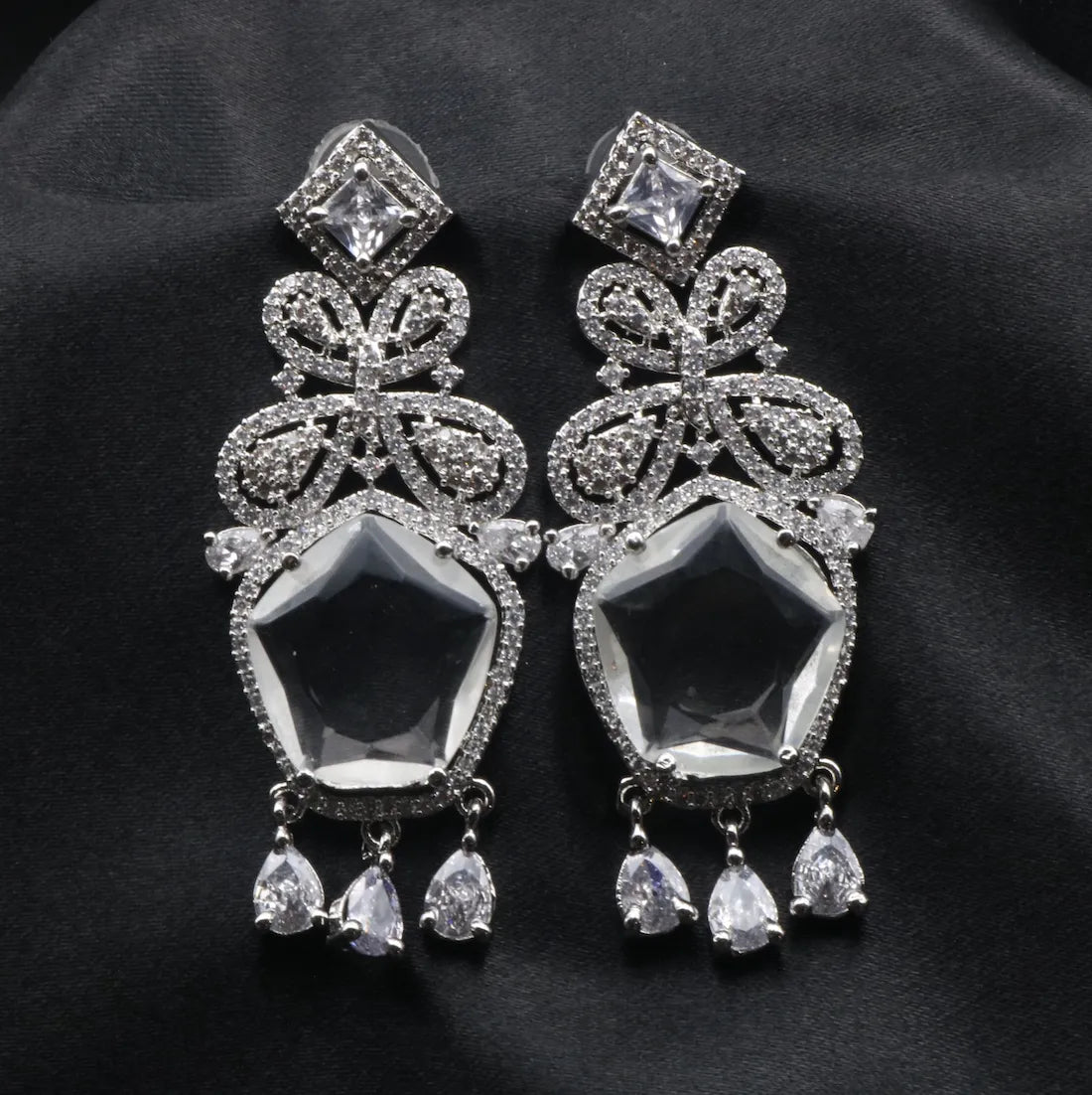 Pair of silver American diamonds earrings with dark gemstones on a black background