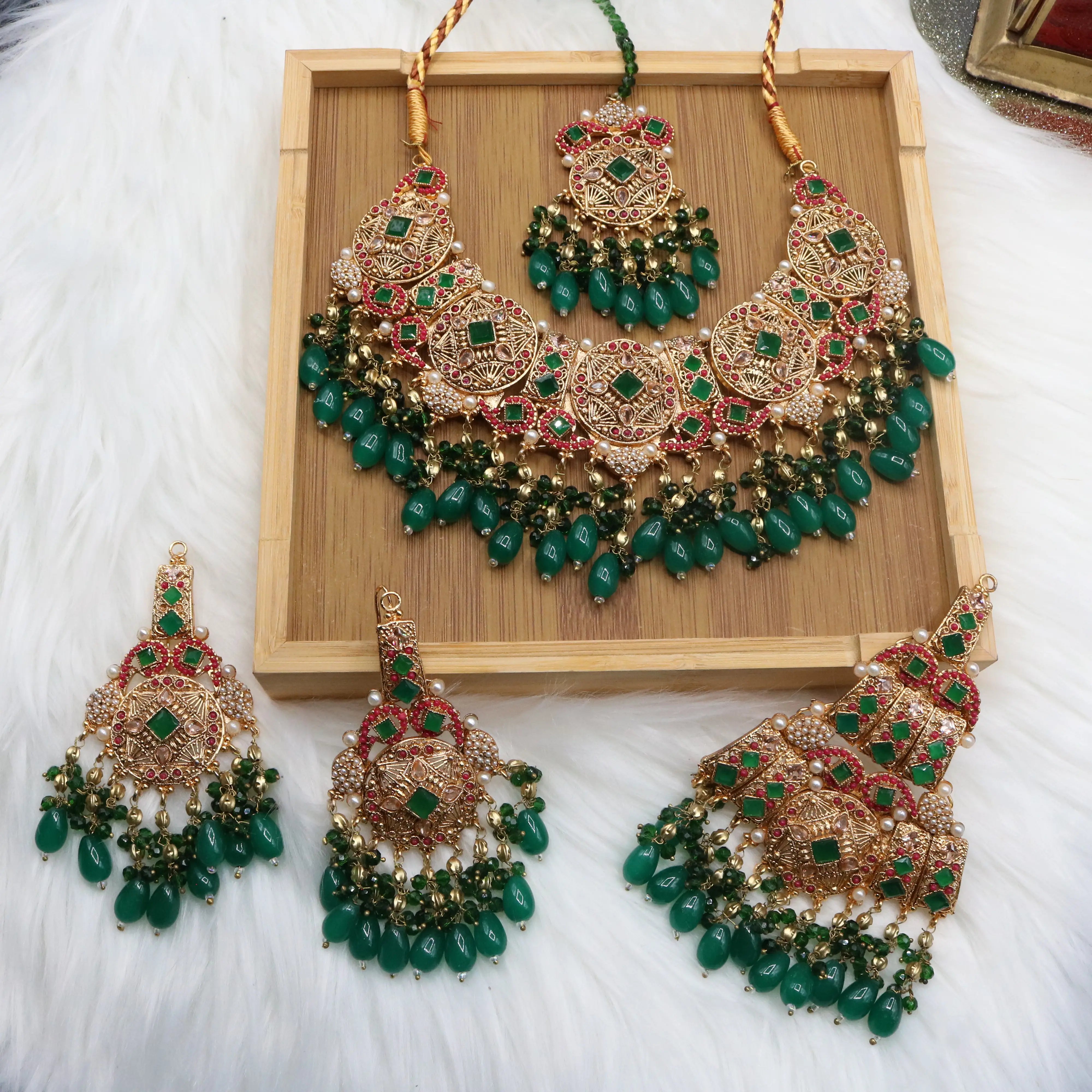 Pakistani bridal set handcrafted with intricate gold-plated detailing, this traditional jewelry set features red stone inlays, sparkling accents, and rich green bead drops