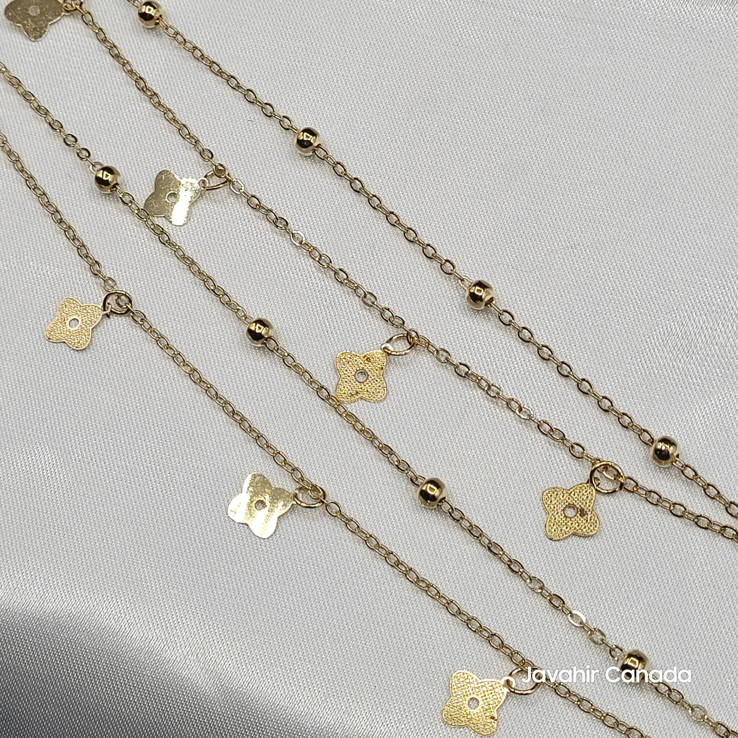 Close-up of JV5017 gold anklets featuring detailed floral charms and small gold beads