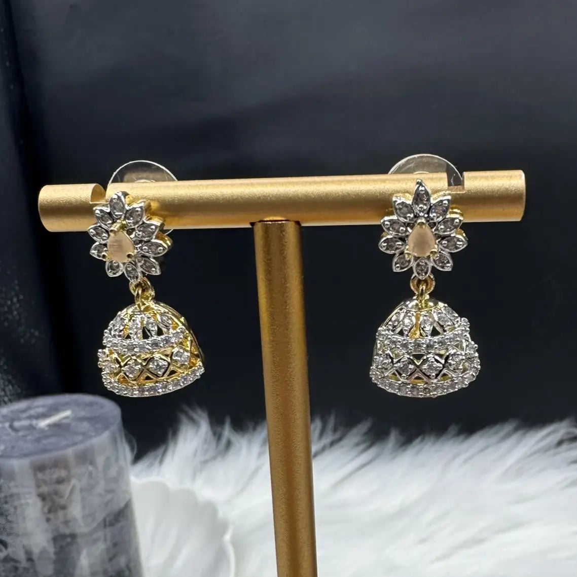 Pair of Pakistani style jhumka earrings with peach gemstones and a gold base with a blurred background