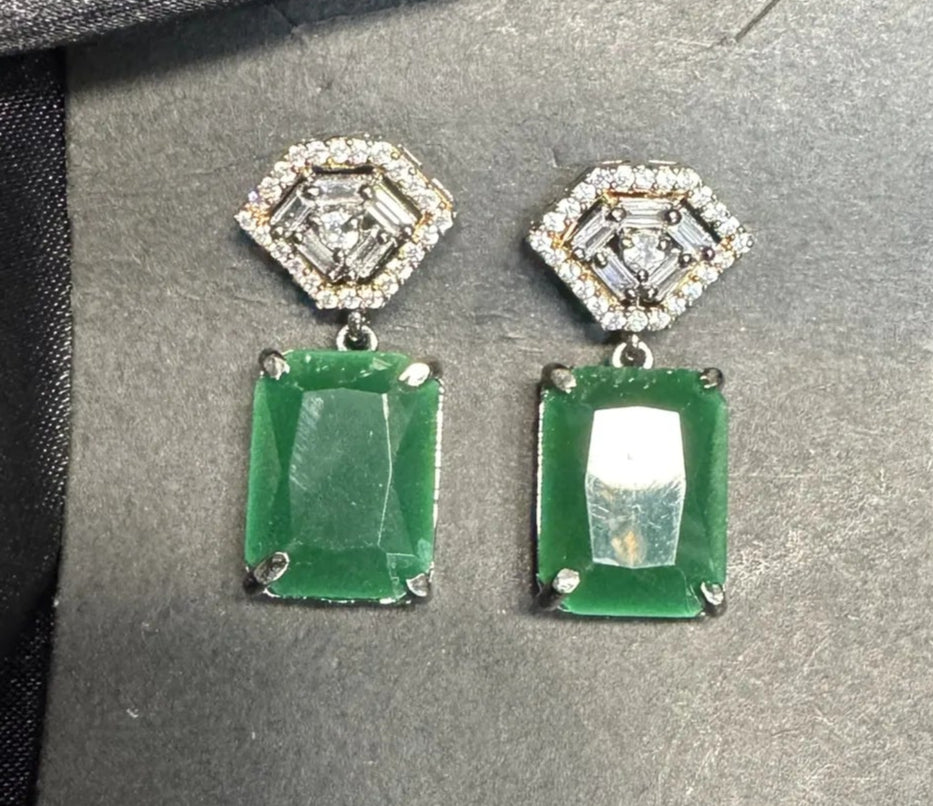 Pair of earrings on a gray card with a black satin background