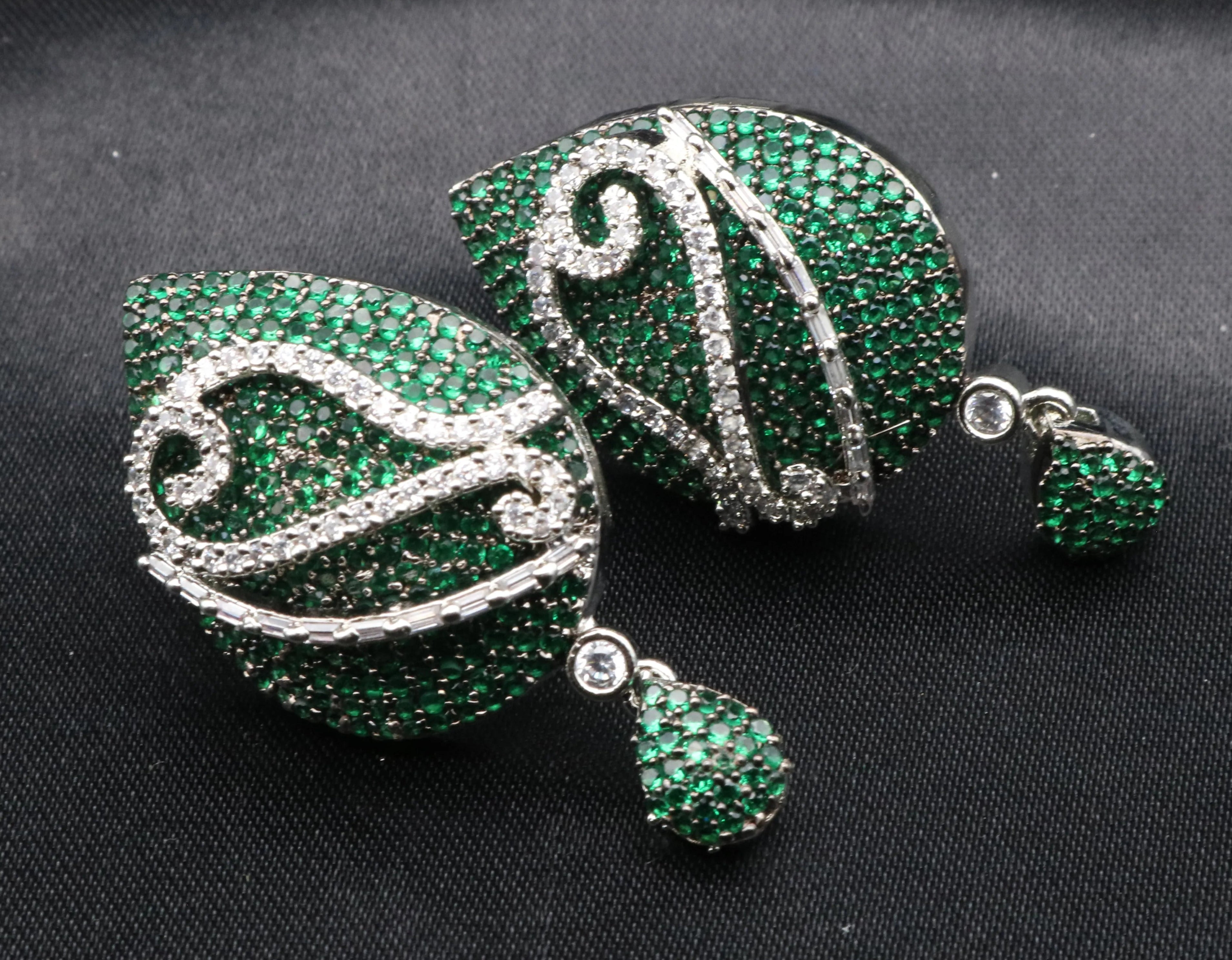 Green and silver American diamonds earrings on a black background
