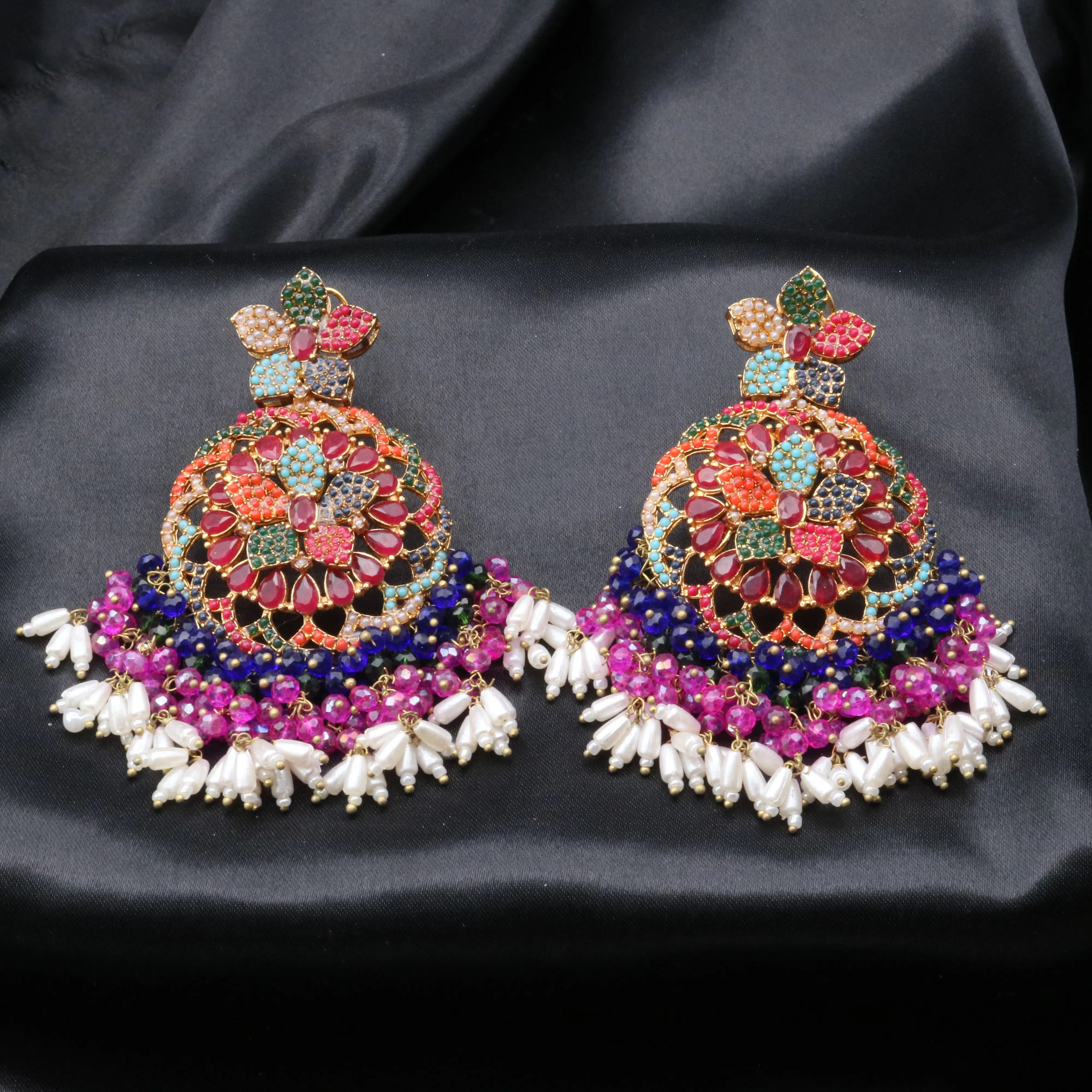 A pair of colorful floral based Pakistani style earrings displayed on a black background.