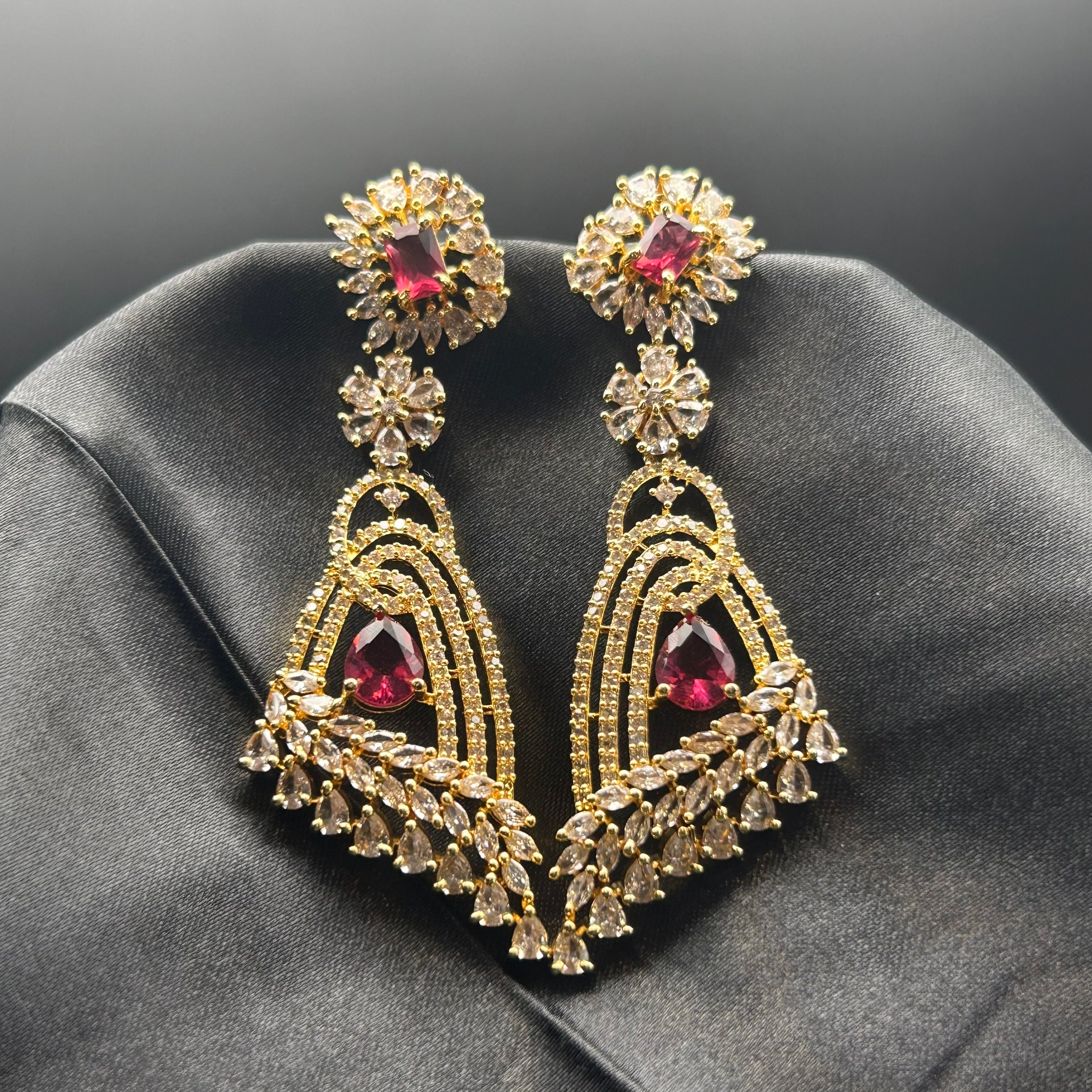 gold plated jarao earrings with red gemstones on a silk cloth