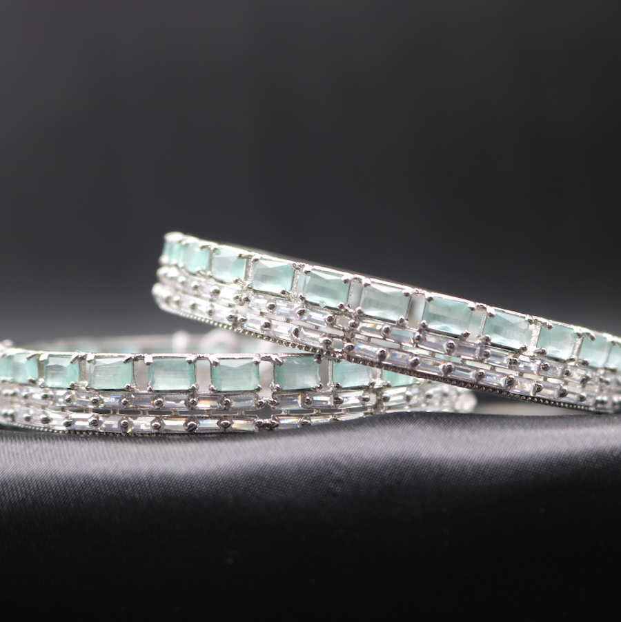 A stainless steel bangles adorned with shimmering American diamonds and teal gemstones.