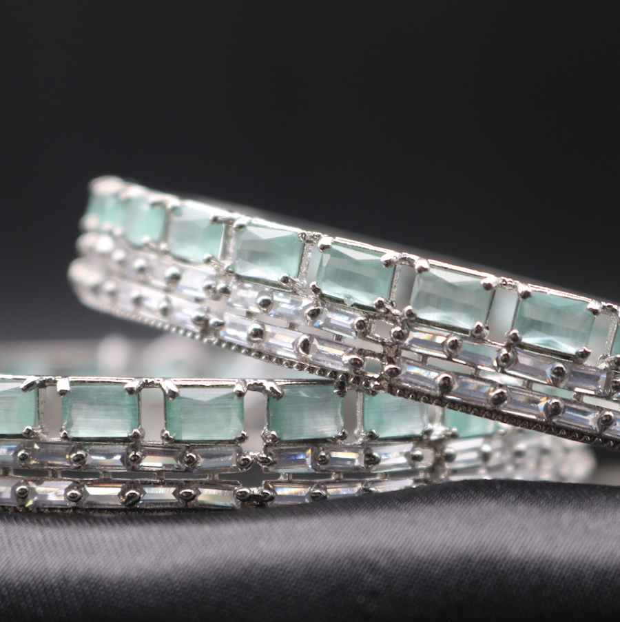 A closer view of stainless steel bangles adorned with shimmering American diamonds and teal gemstones.