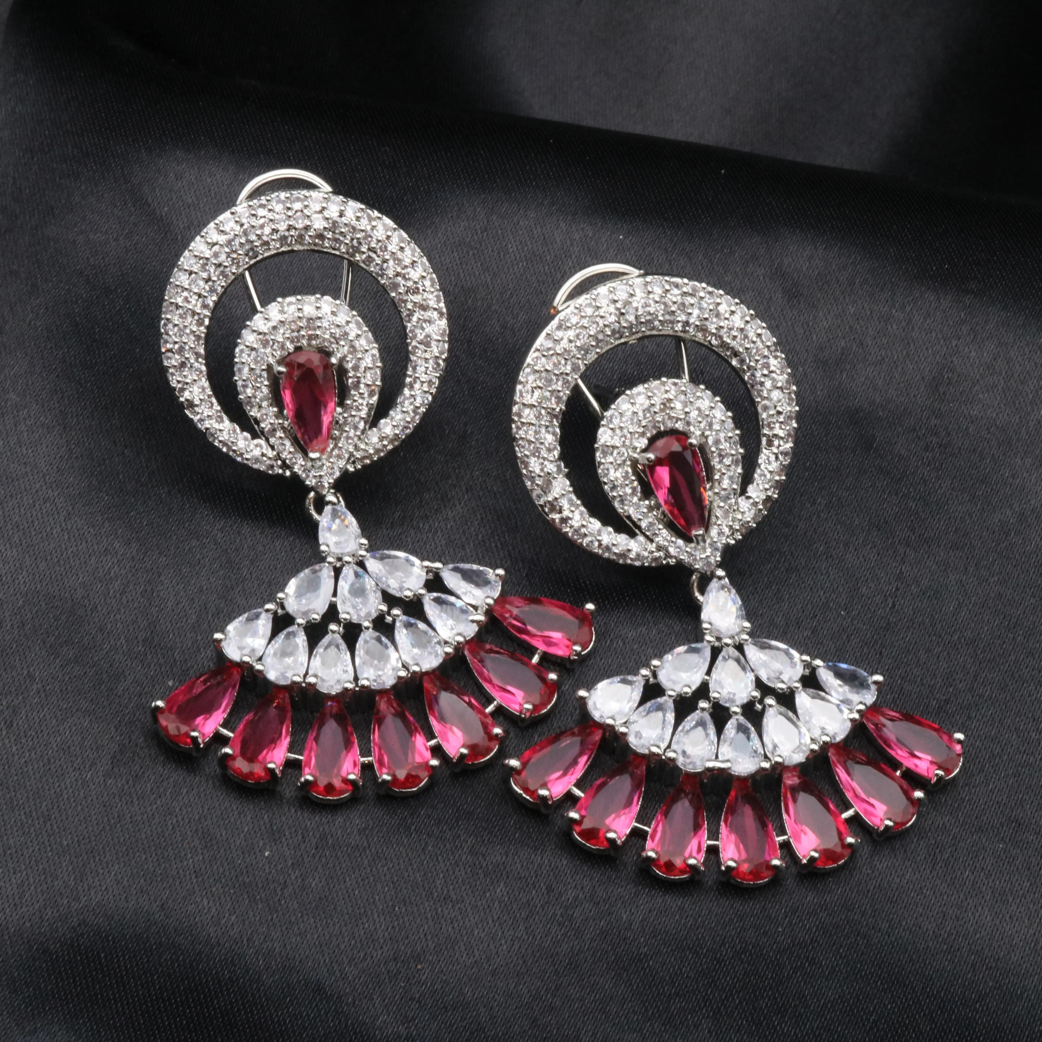 Pair of silver and hotpink earrings on a black background