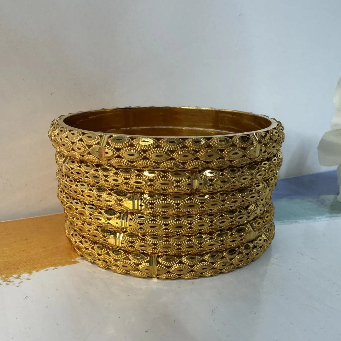 Set of 6 22k gold plated bangles on a white surface with a light gray background