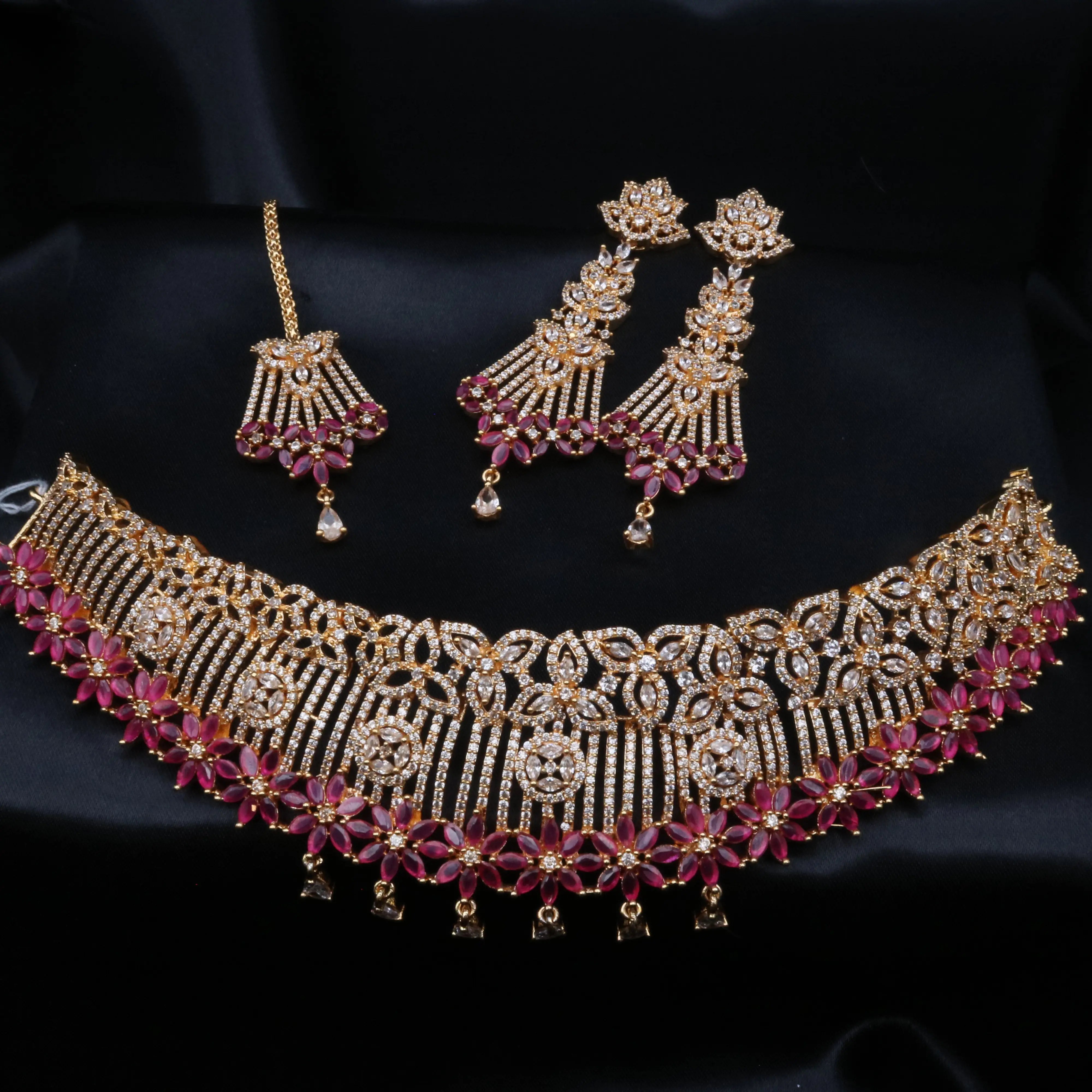 Cherry Blossom necklace set displayed on black velvet featuring ruby-colored floral stones and CZ detailing.