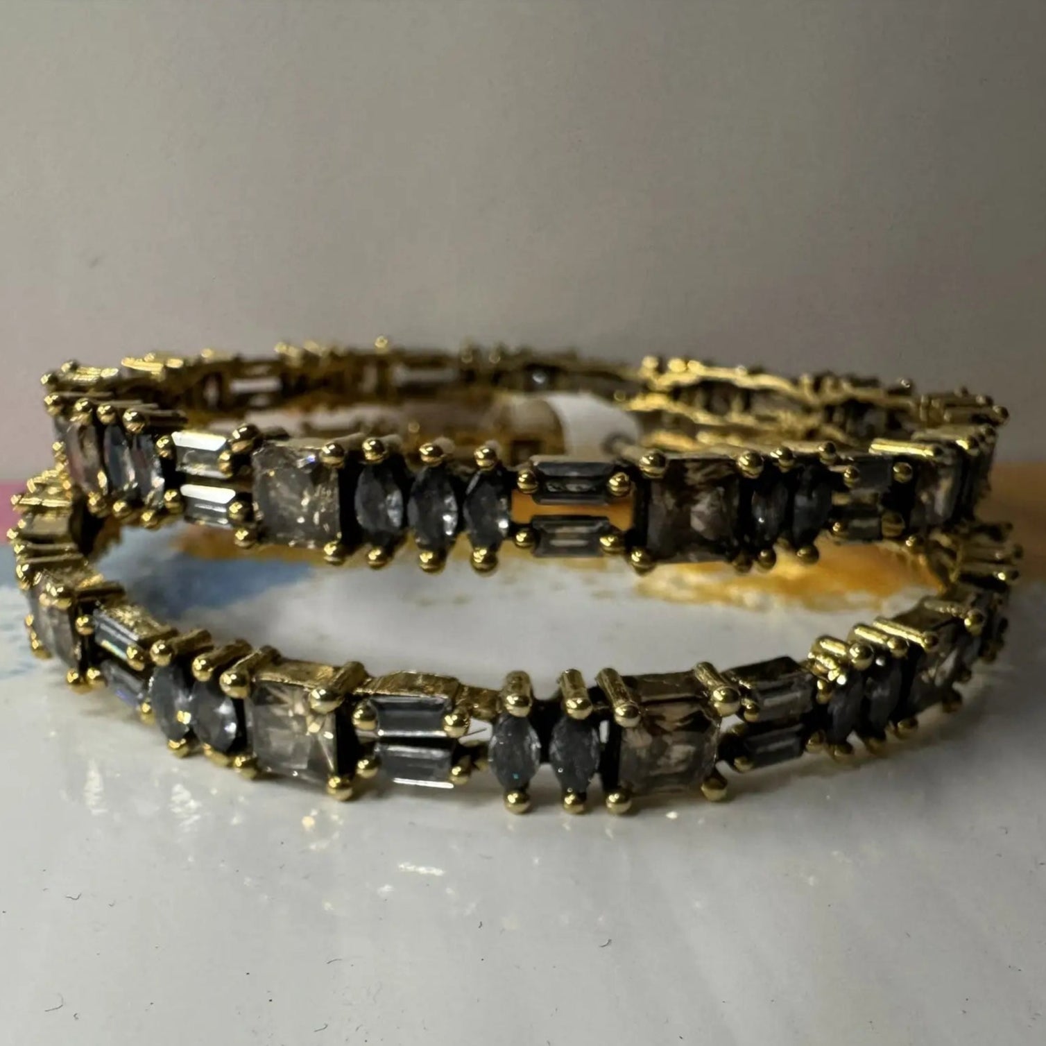 Gold plated bangles with black gemstones on a white surface