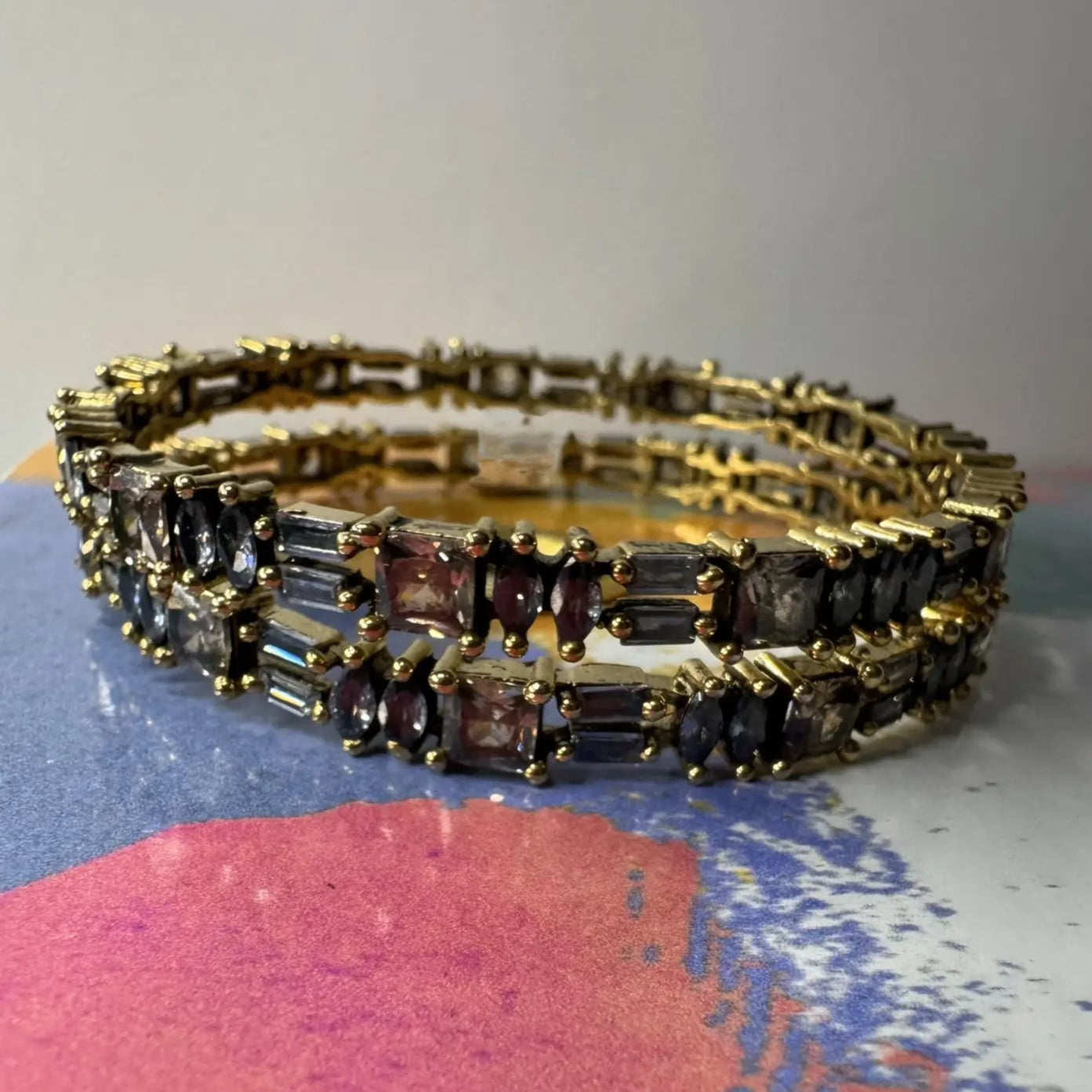Gold plated bangles with black gemstones on a colorful surface