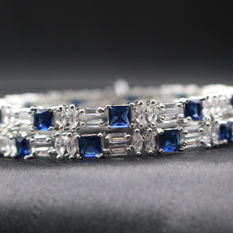 American diamonds bangles with blue gemstones and silver accents on a black surface