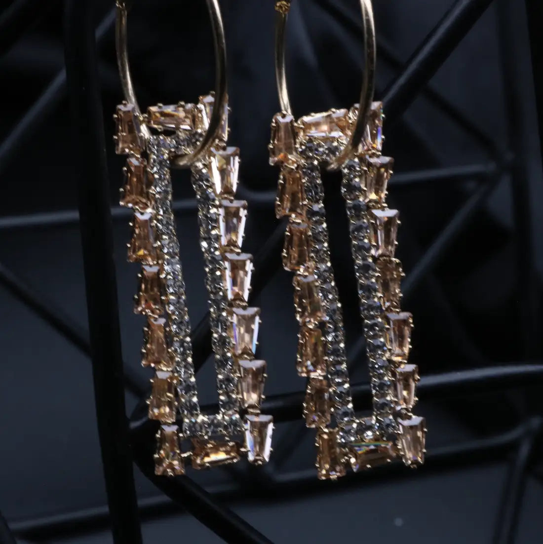 Pair of gold and champagne earrings on a dark background