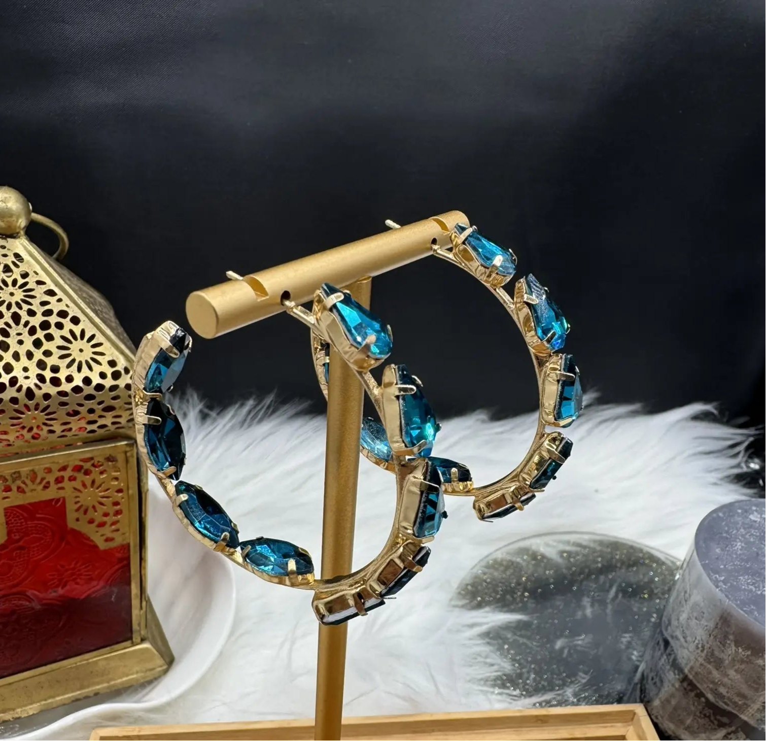 Gold earring with blue gemstones on a stand against a dark background