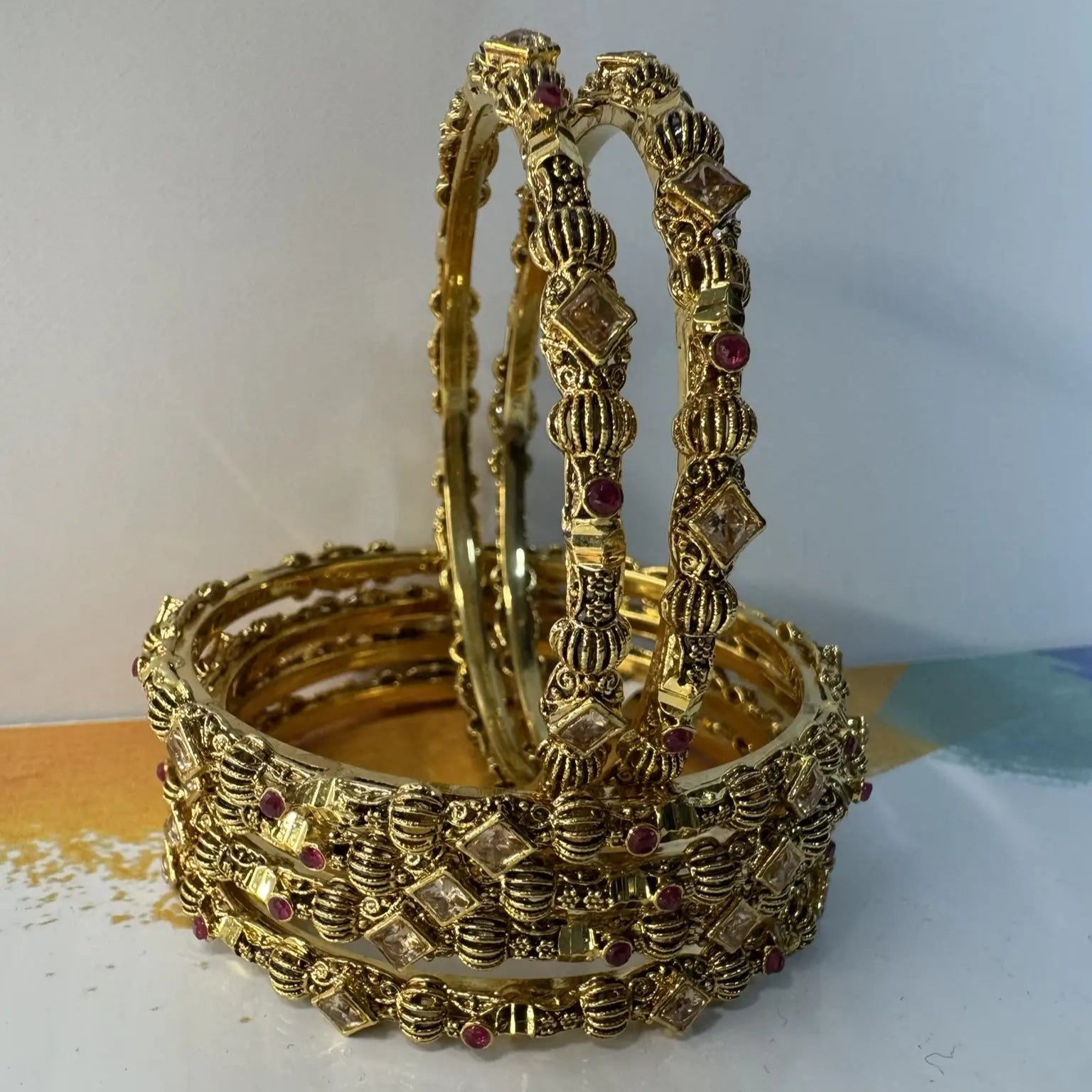 Set of gold bangles with intricate designs on a white surface