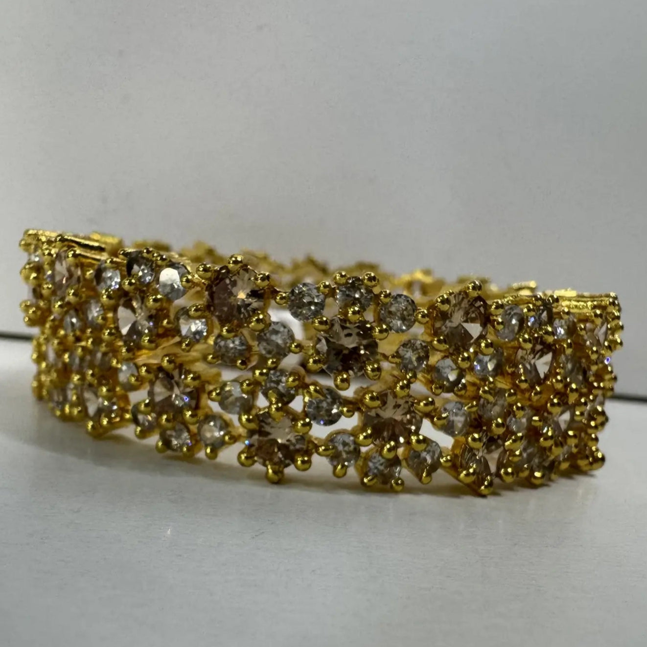 side view of gold-plated and American diamond bangle set on a white background