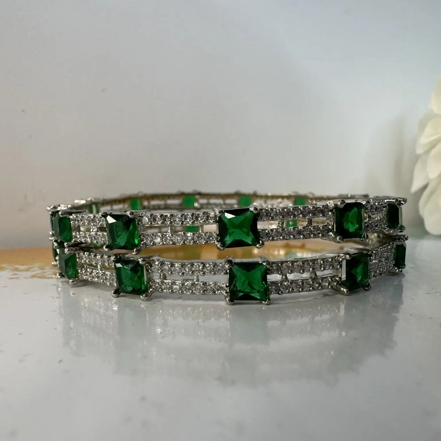 Bangles with green gemstones on a light surface
