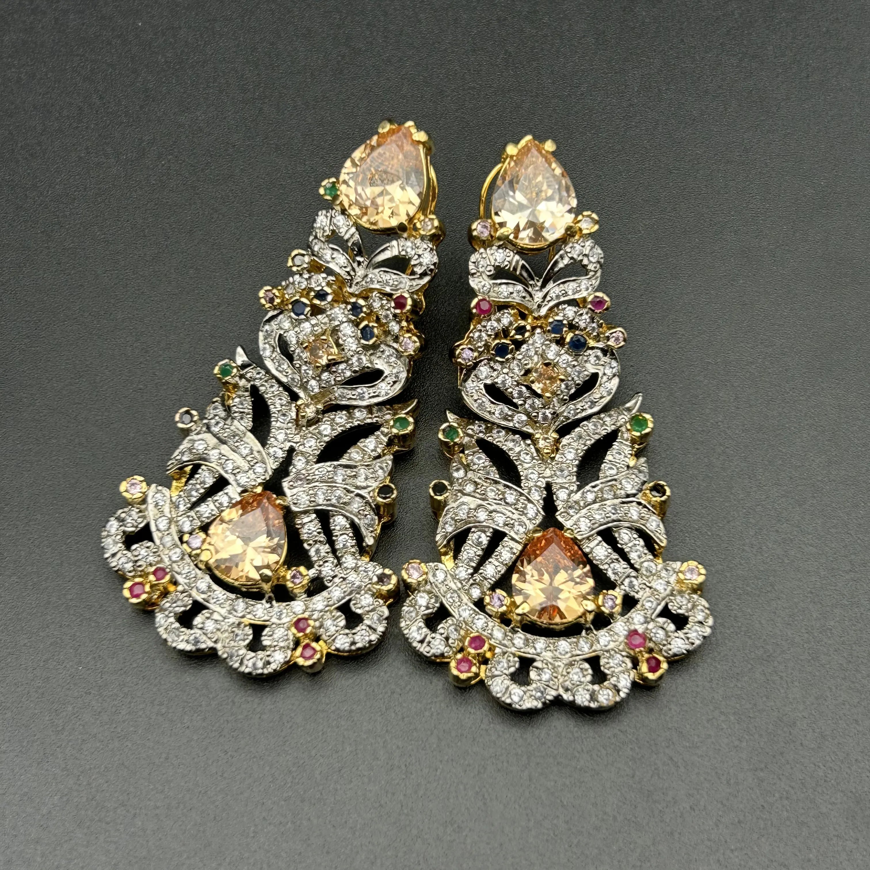 Pair of ornate earrings with gemstones on a gray background