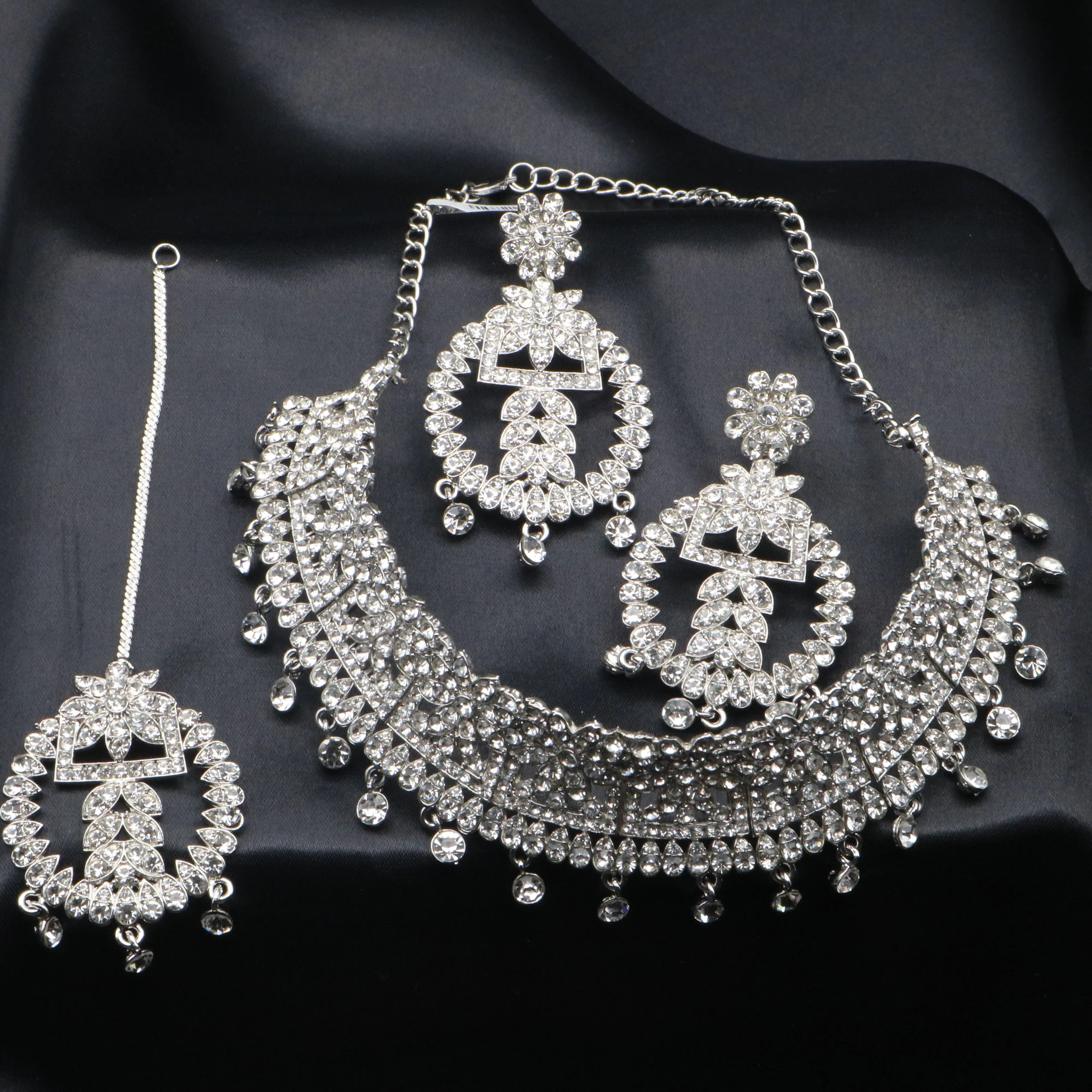 Sage American diamond necklace set with earrings and tikka laid out on black satin