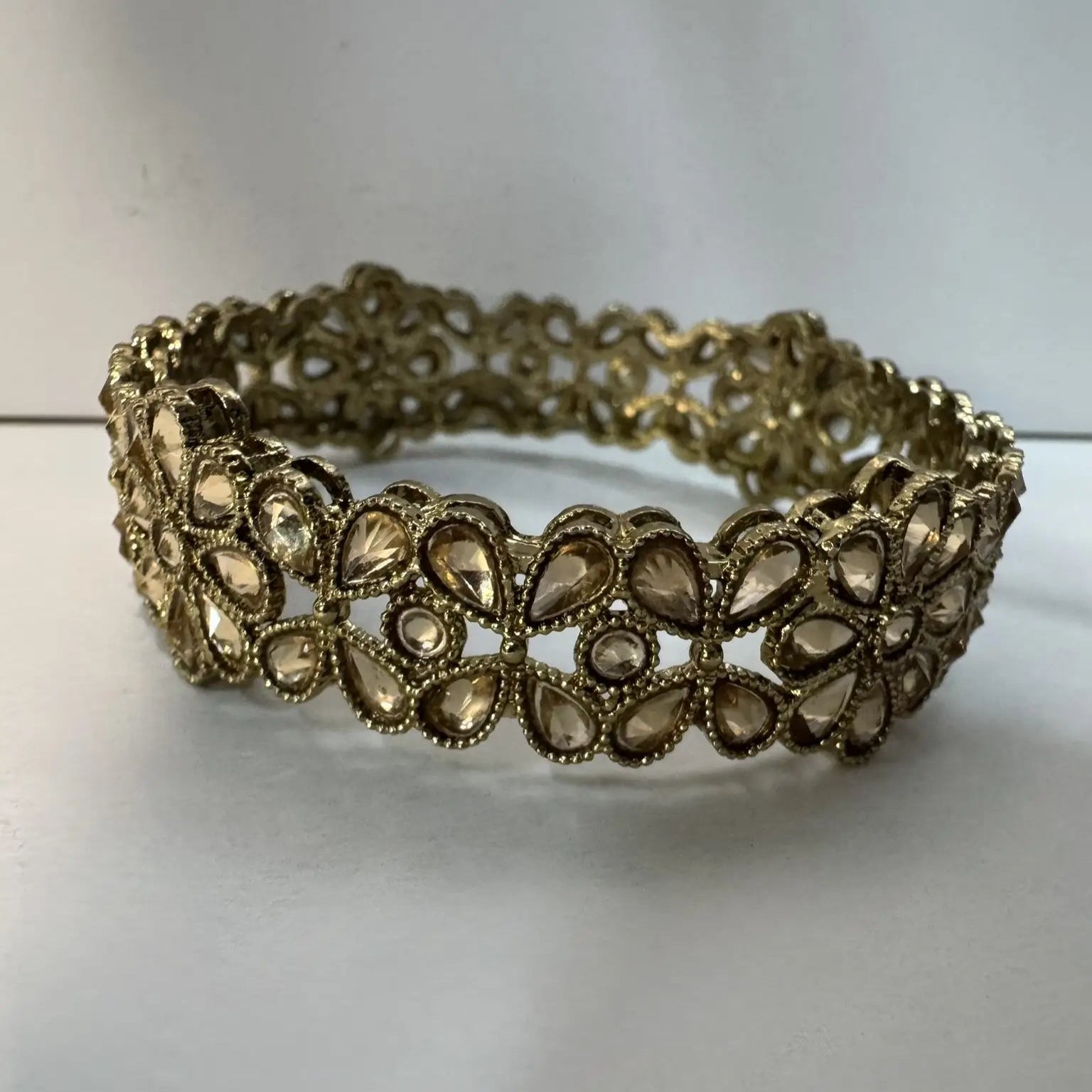 Gold plated bangle with clear gemstones on a white background