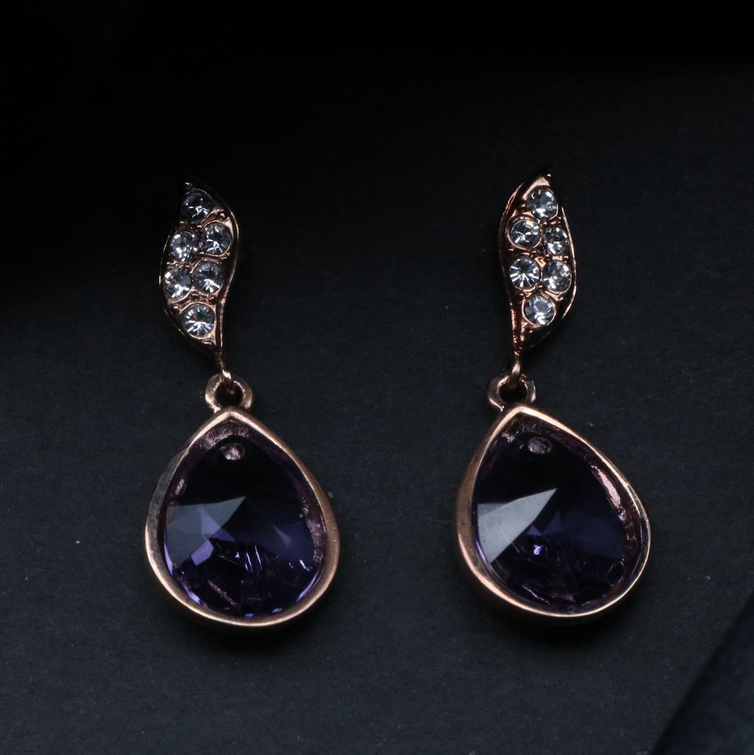 top view of a pair of gold-plated stainless steel earrings with American diamonds set in a classic drop style.