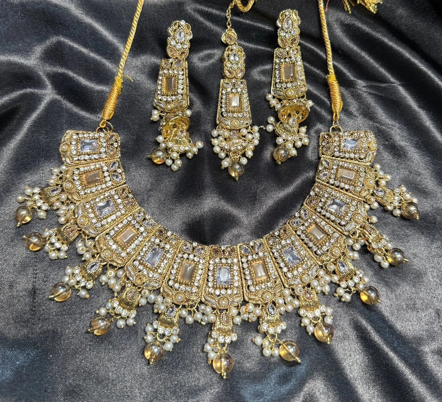 Flat lay of Vixen necklace set with rectangular stones, pearl drops, and complete teeka