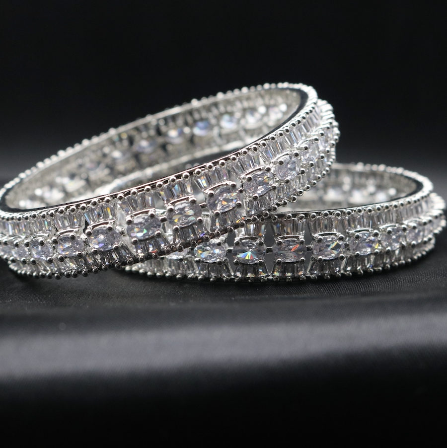 A set of stainless steel bangles adorned with sparkling American diamonds, displayed against a dark background.