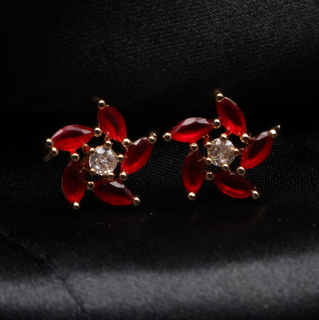 gold-plated with red gemstones studs on a black card