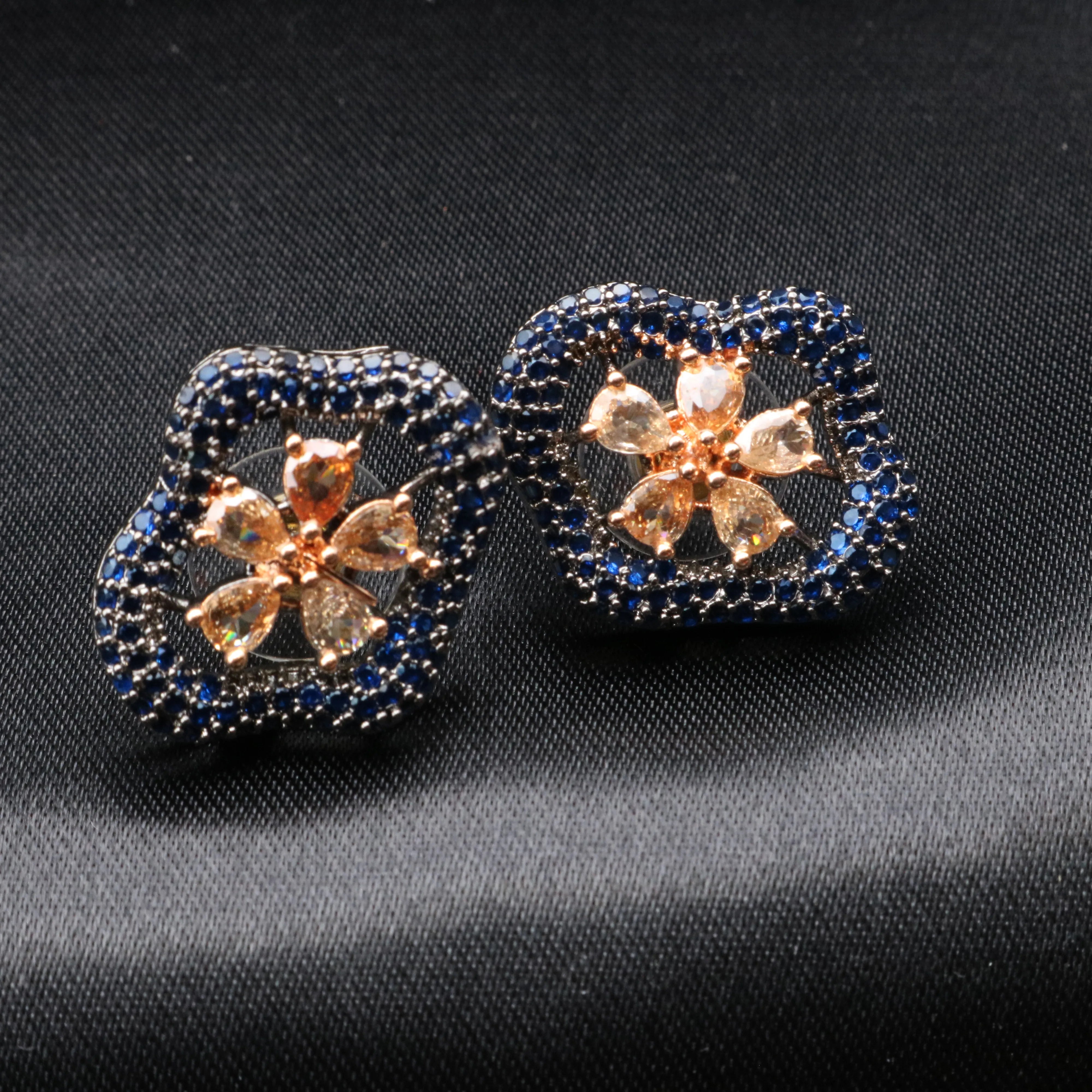 Pair of decorative earrings with floral design on a dark fabric background