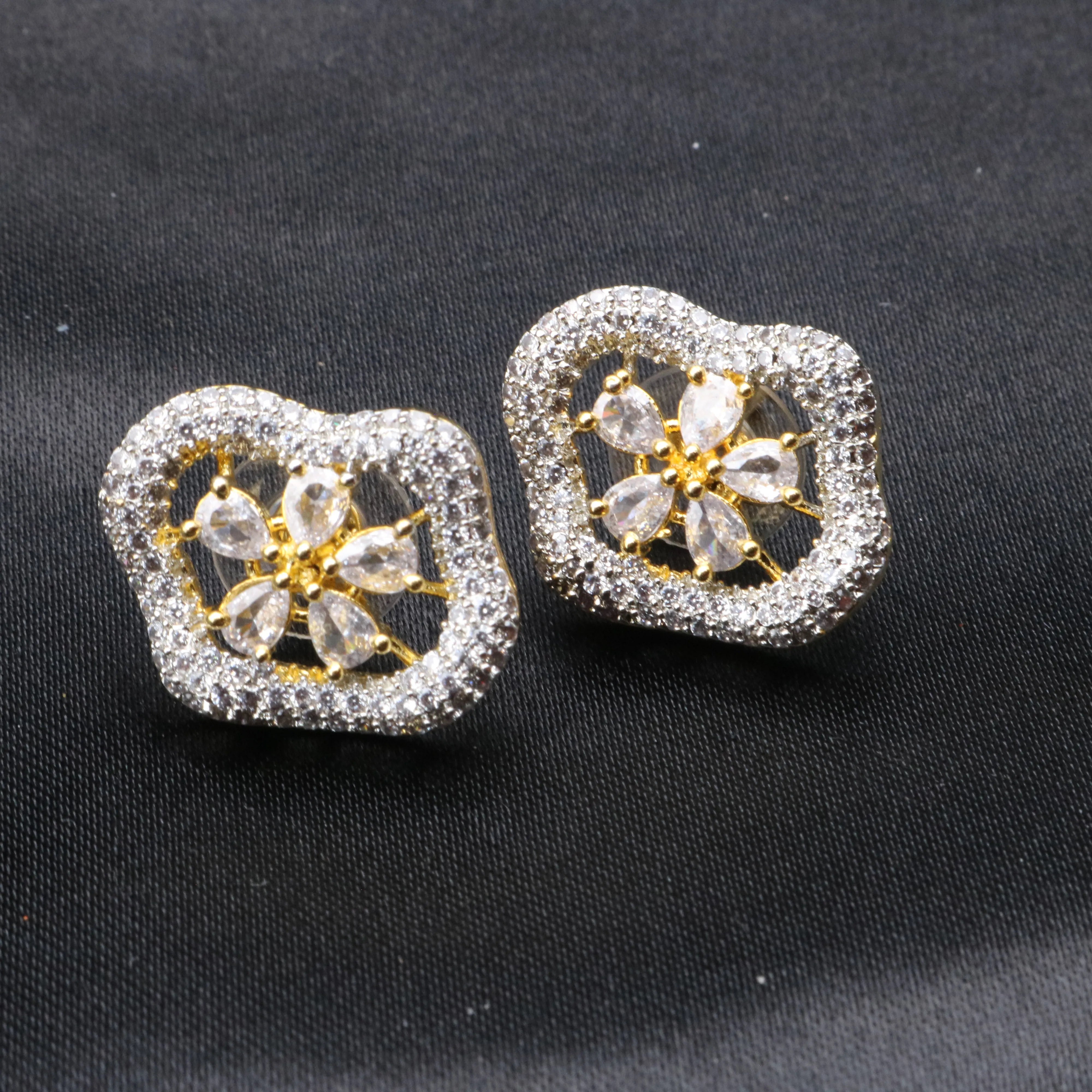 Pair of silver and gold earrings on a black background