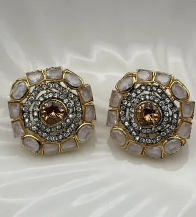 Pair of ornate gold-plated and American diamonds earrings with gemstones on a white background
