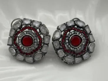 Pair of gold-plated and American diamonds earrings with red center and silver surround on a white background