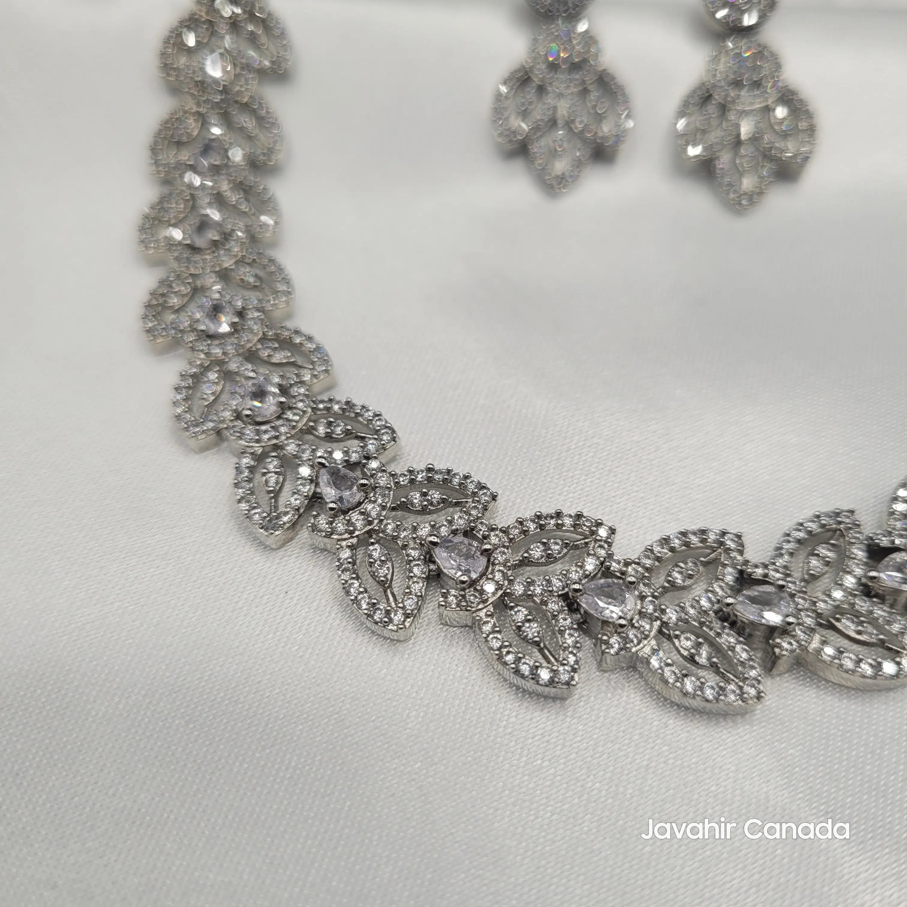 Detail shot of the necklace's leaf motif with zircon stones on white satin.