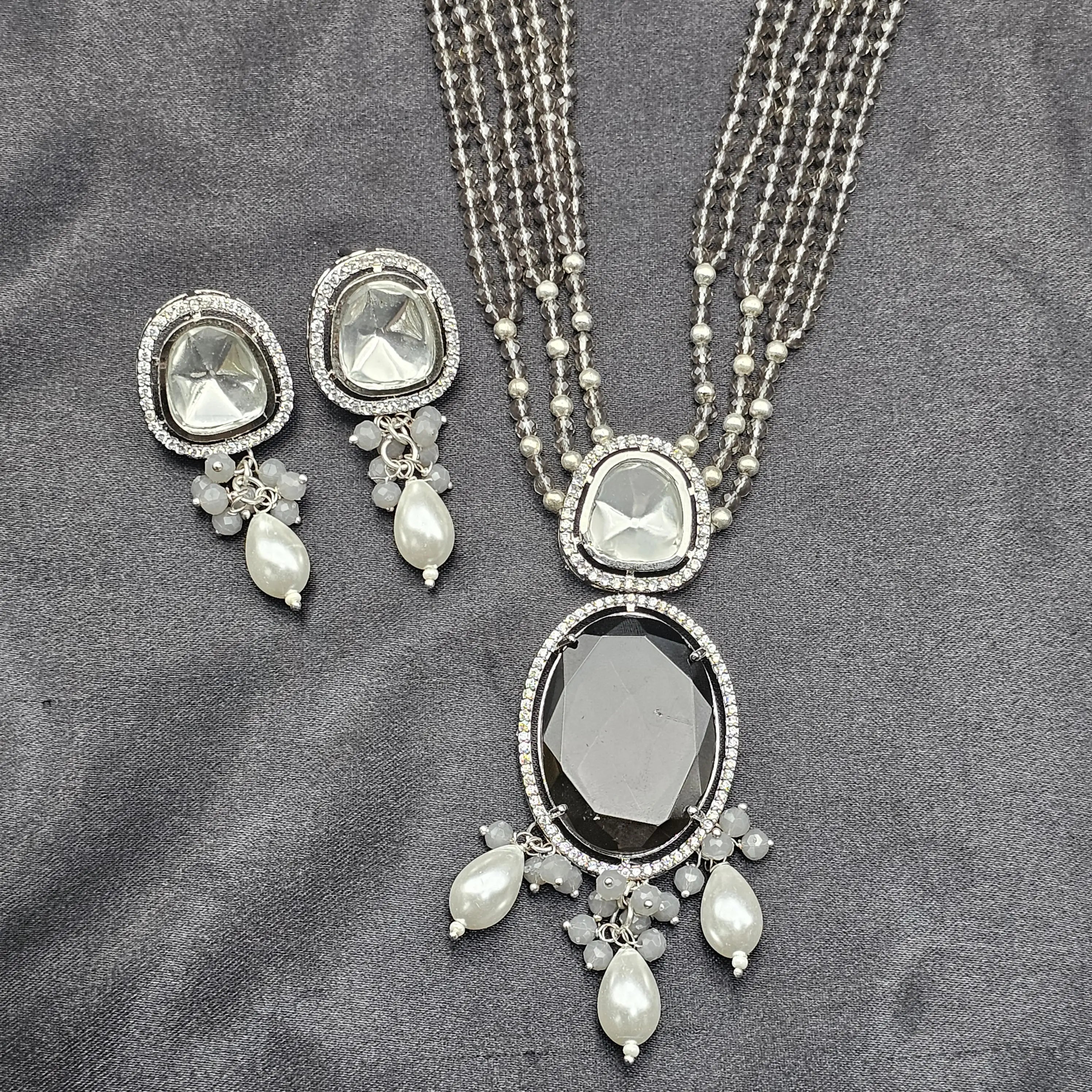 Caspian necklace set in smoky grey with large brown center stone, pearl drops, and matching earrings on grey background.