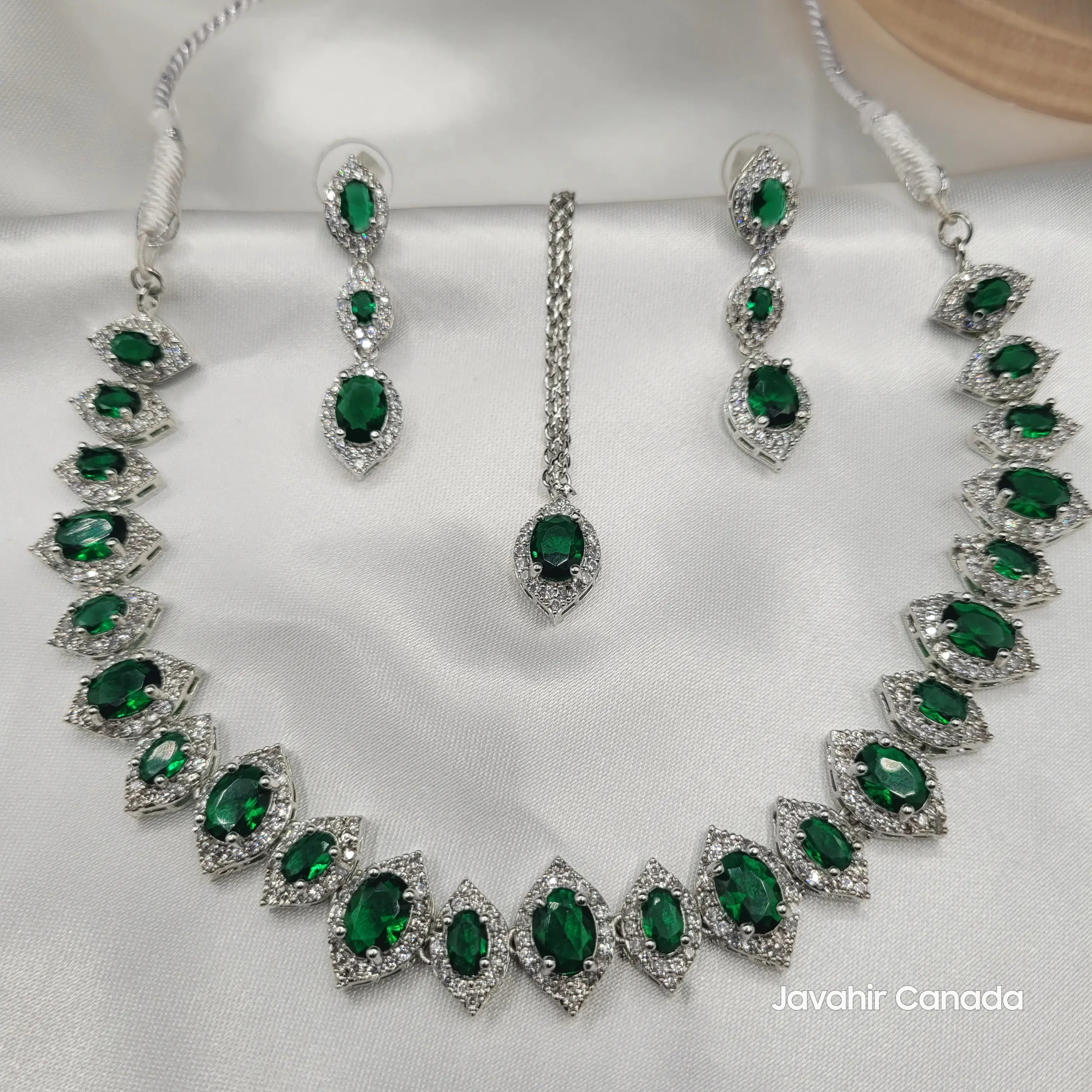 Overhead view of Camellia CZ necklace set with green stones and silver accents