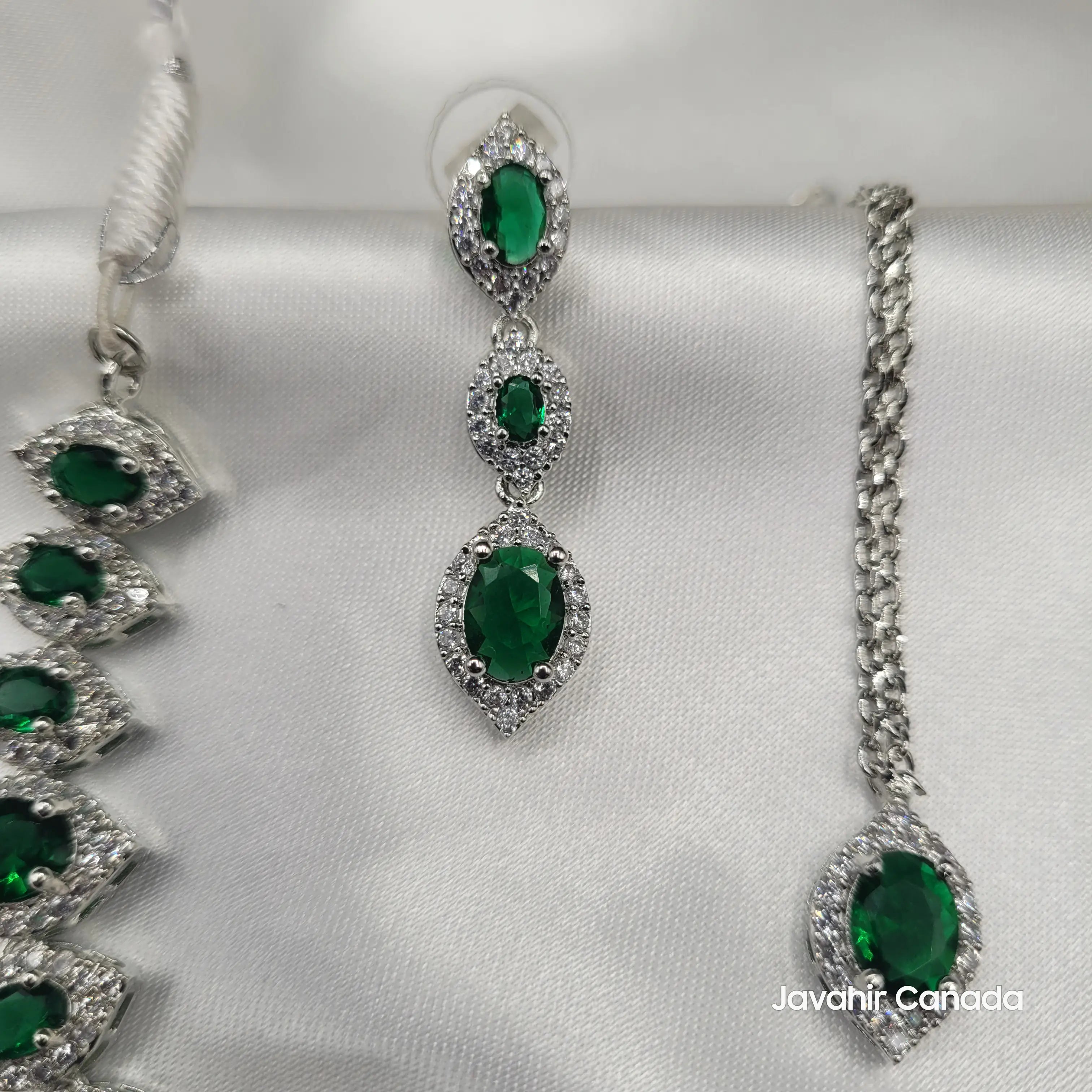 Detailed shot of Camellia drop earrings with oval and marquise green CZ stones