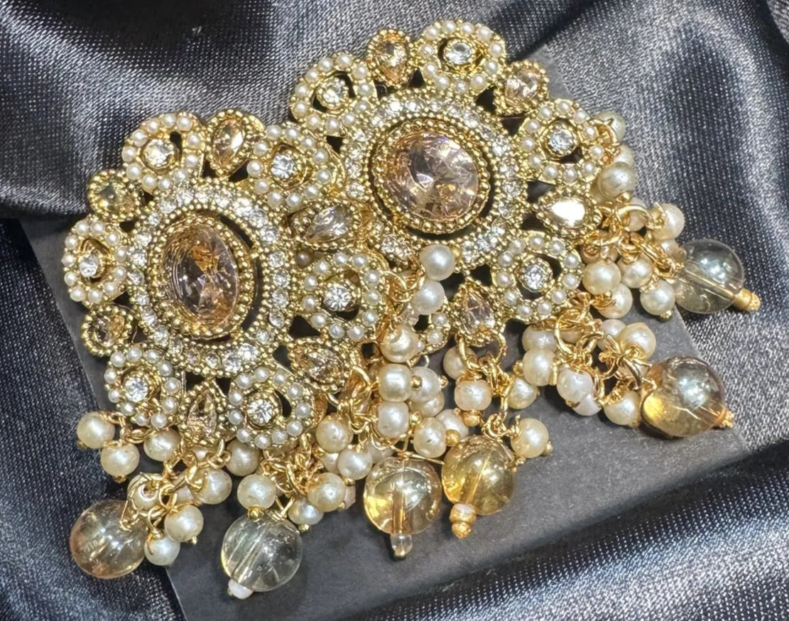 Gold and pearl earrings on a dark satin fabric