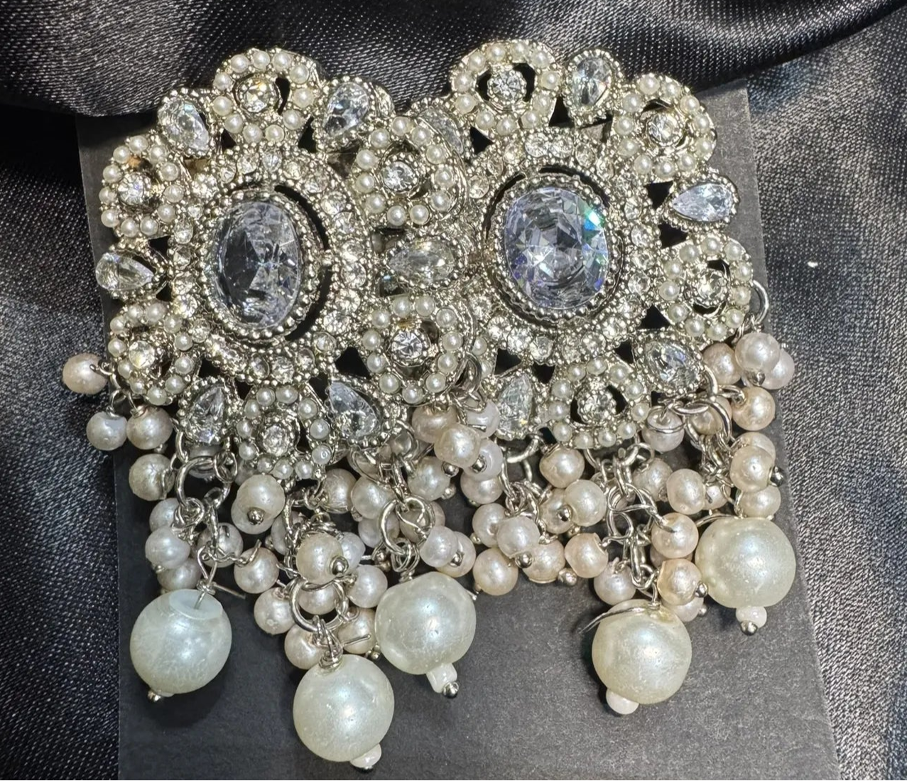 Earrings with pearls and gemstones on a black satin background