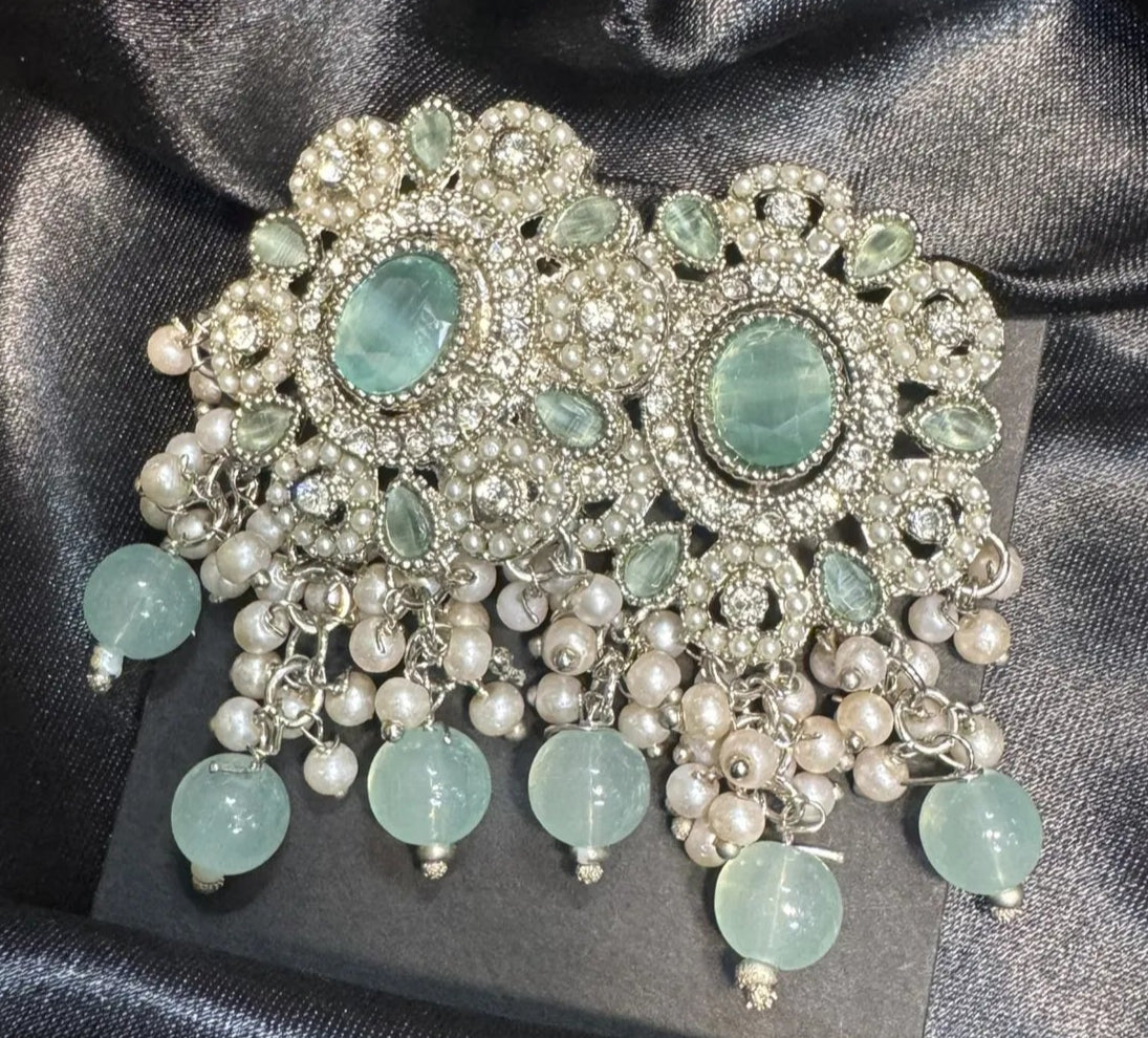 Earrings with turquoise stones and pearl-like elements on a black satin background