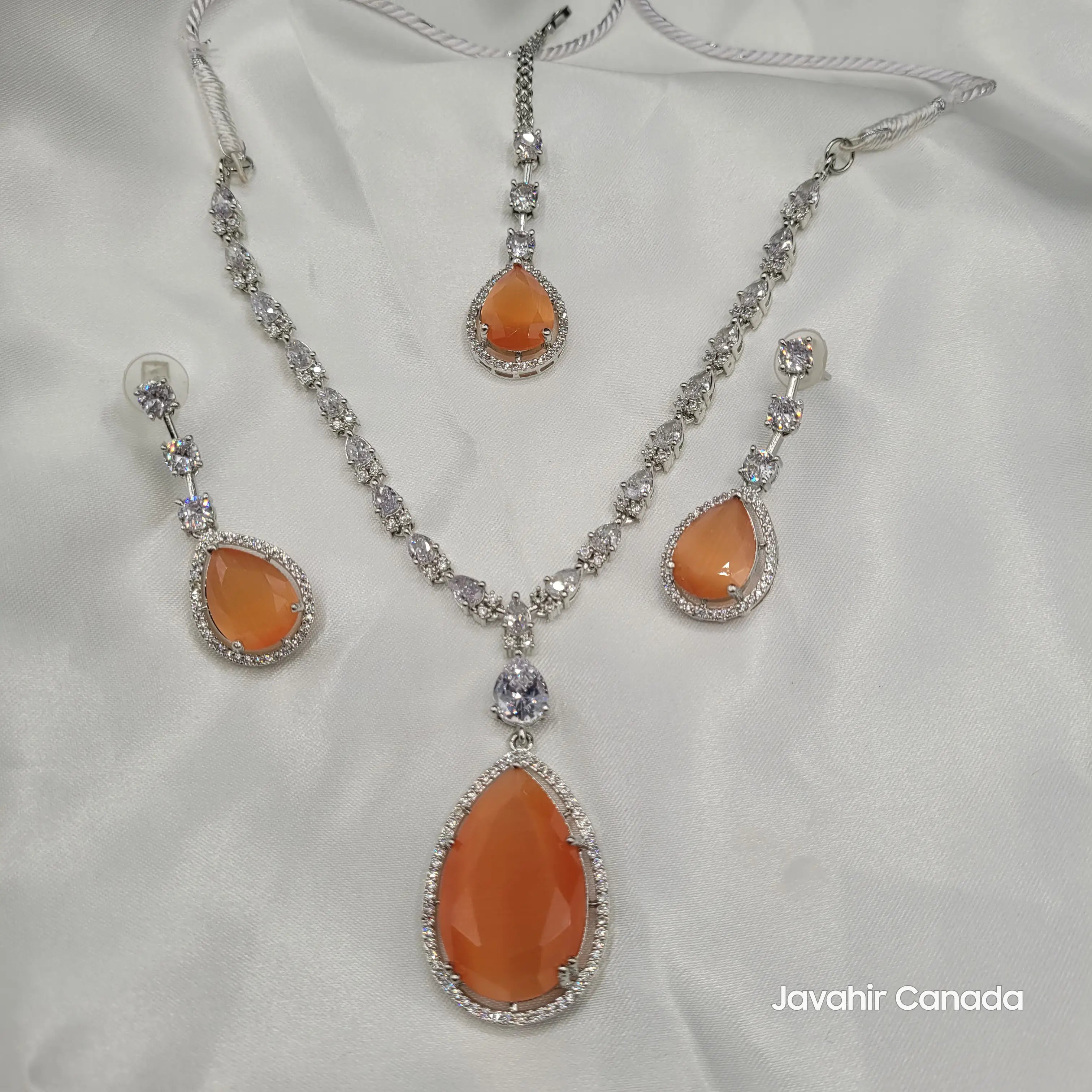 Full Chaos necklace set in burnt orange with earrings and maang tikka on white fabric.