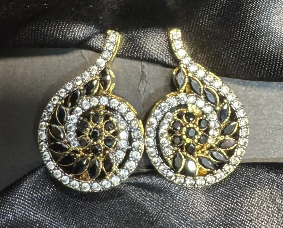 Gold and silver earrings on a black satin background