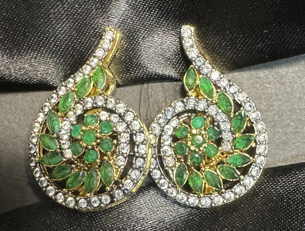 Pair of green gemstone earrings with gold accents on a black satin background