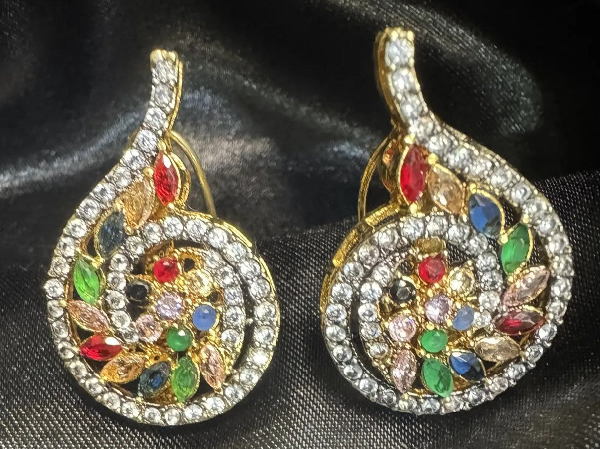 Pair of ornate earrings with colorful gemstones on a black background
