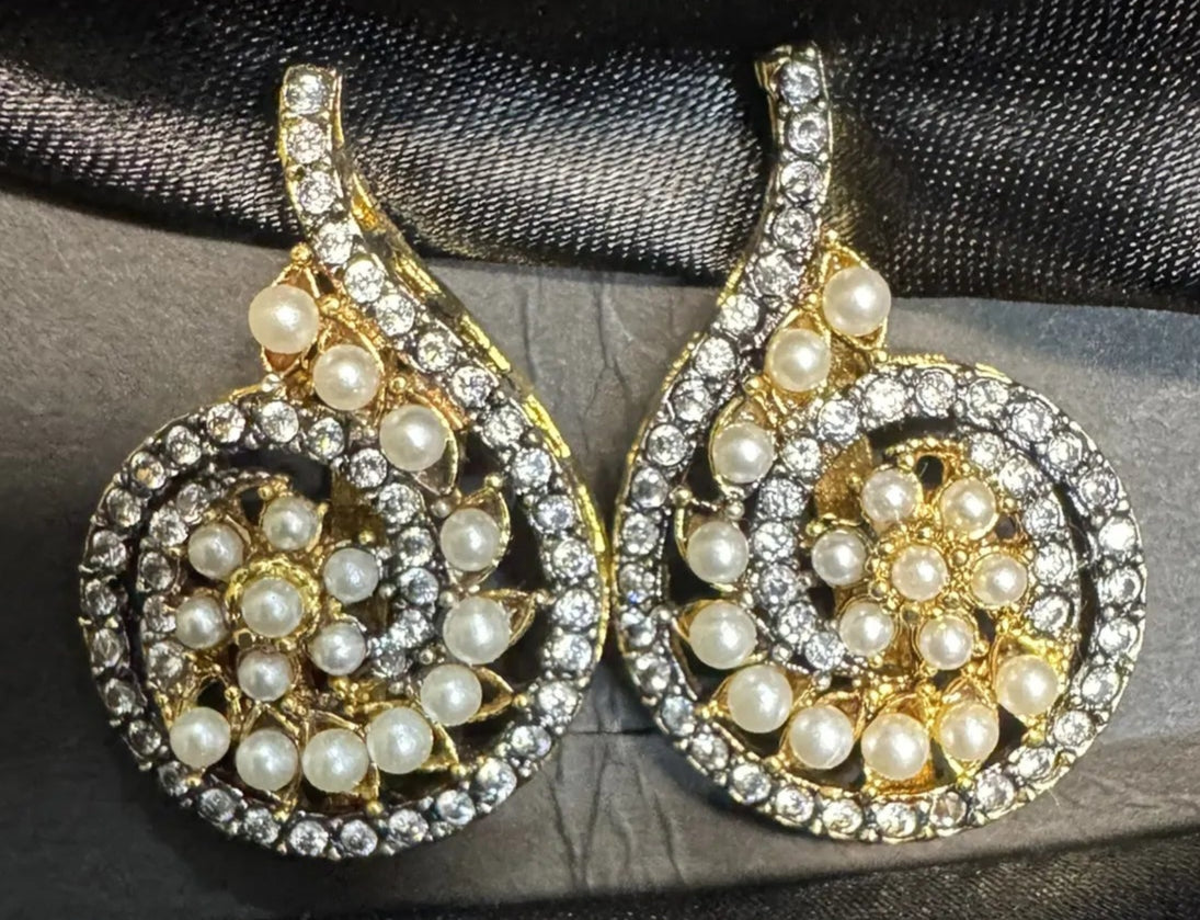Gold and pearl earrings on a black satin background
