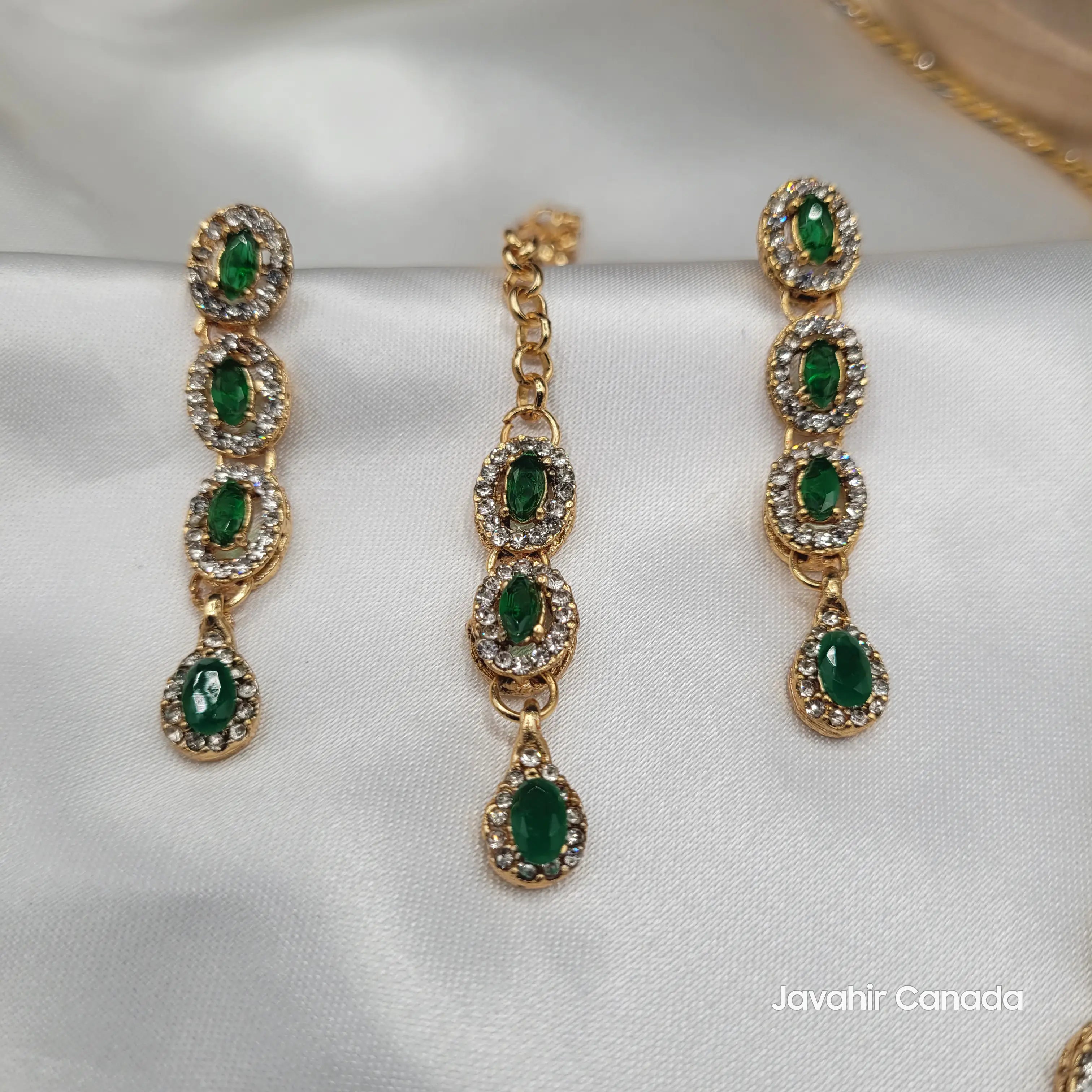Close-up of Daint earring set and teeka with green oval and teardrop CZ stones in gold finish