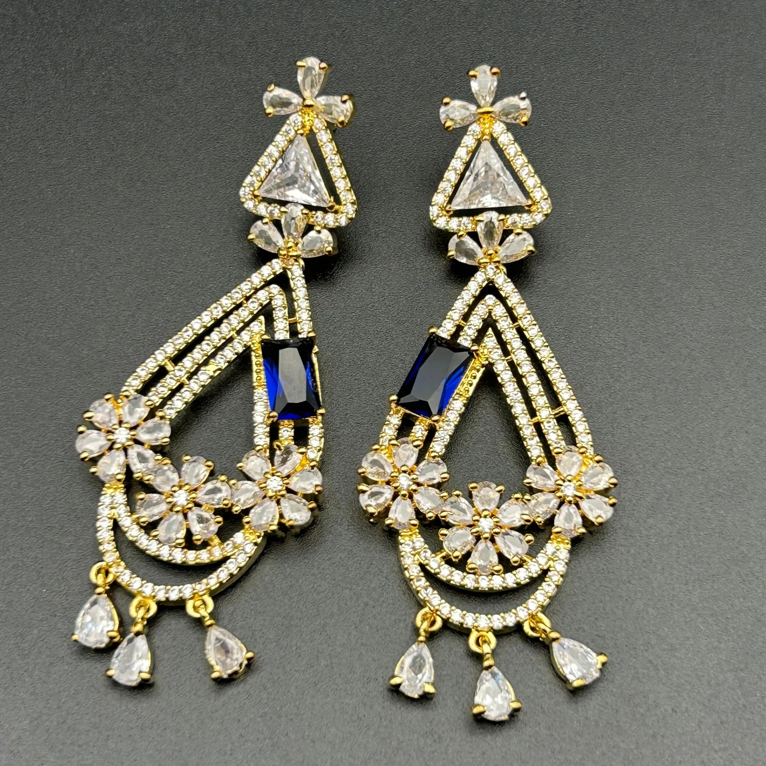 Pair of ornate earrings with blue gemstones on a gray background