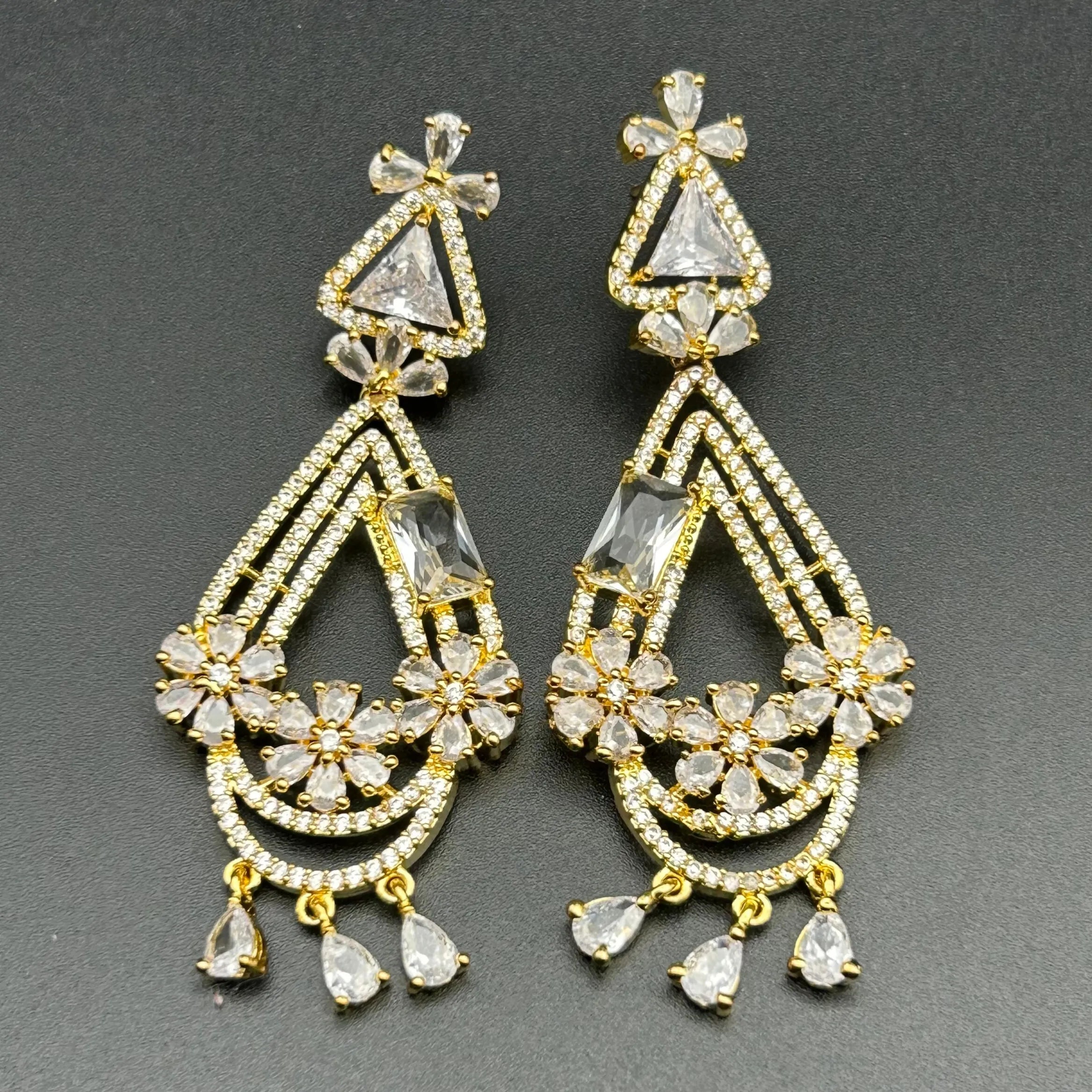 Pair of gold plated and crystal earrings on a gray background
