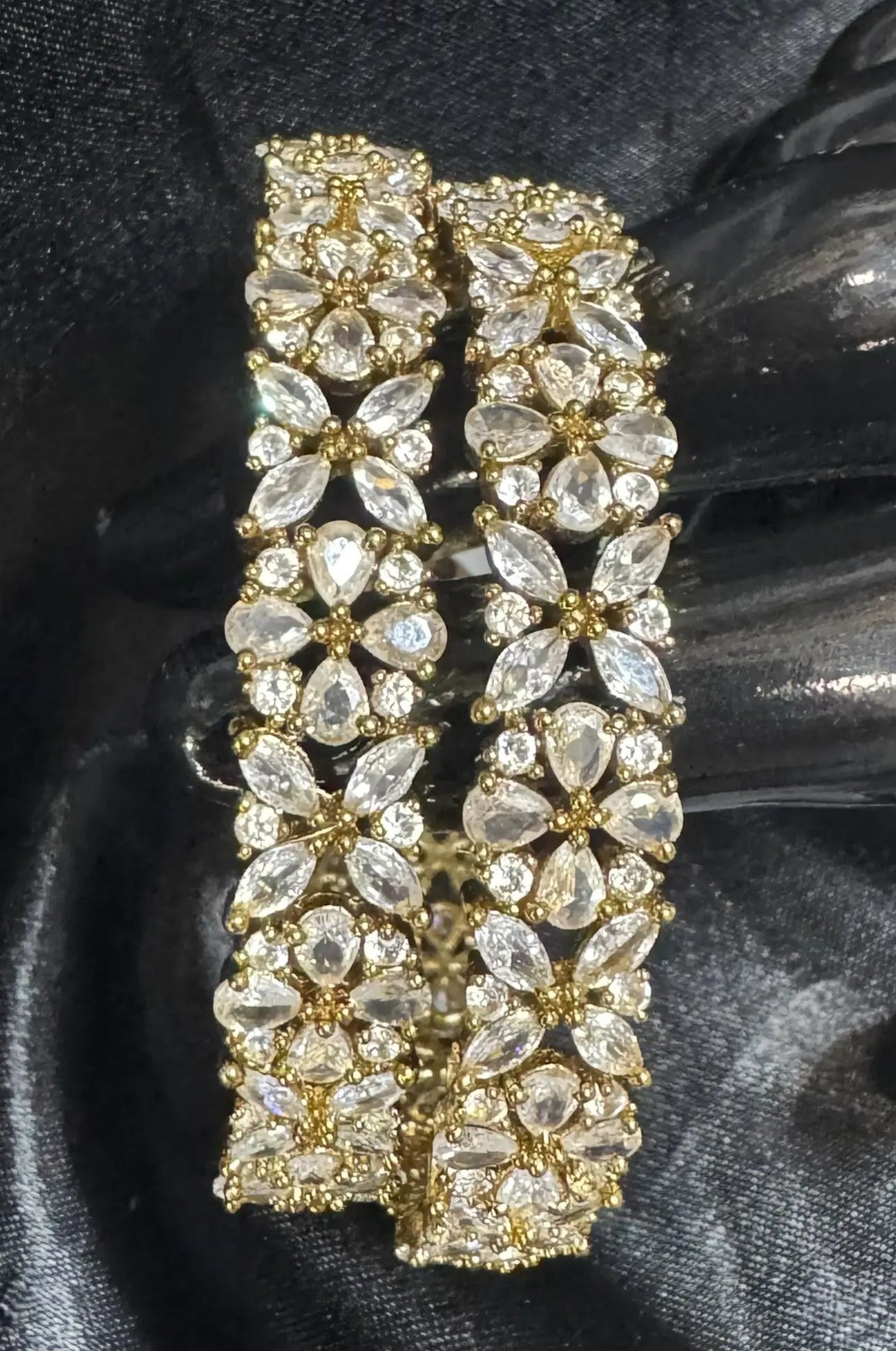 Gold-plated and crystal bangles on a black satin background